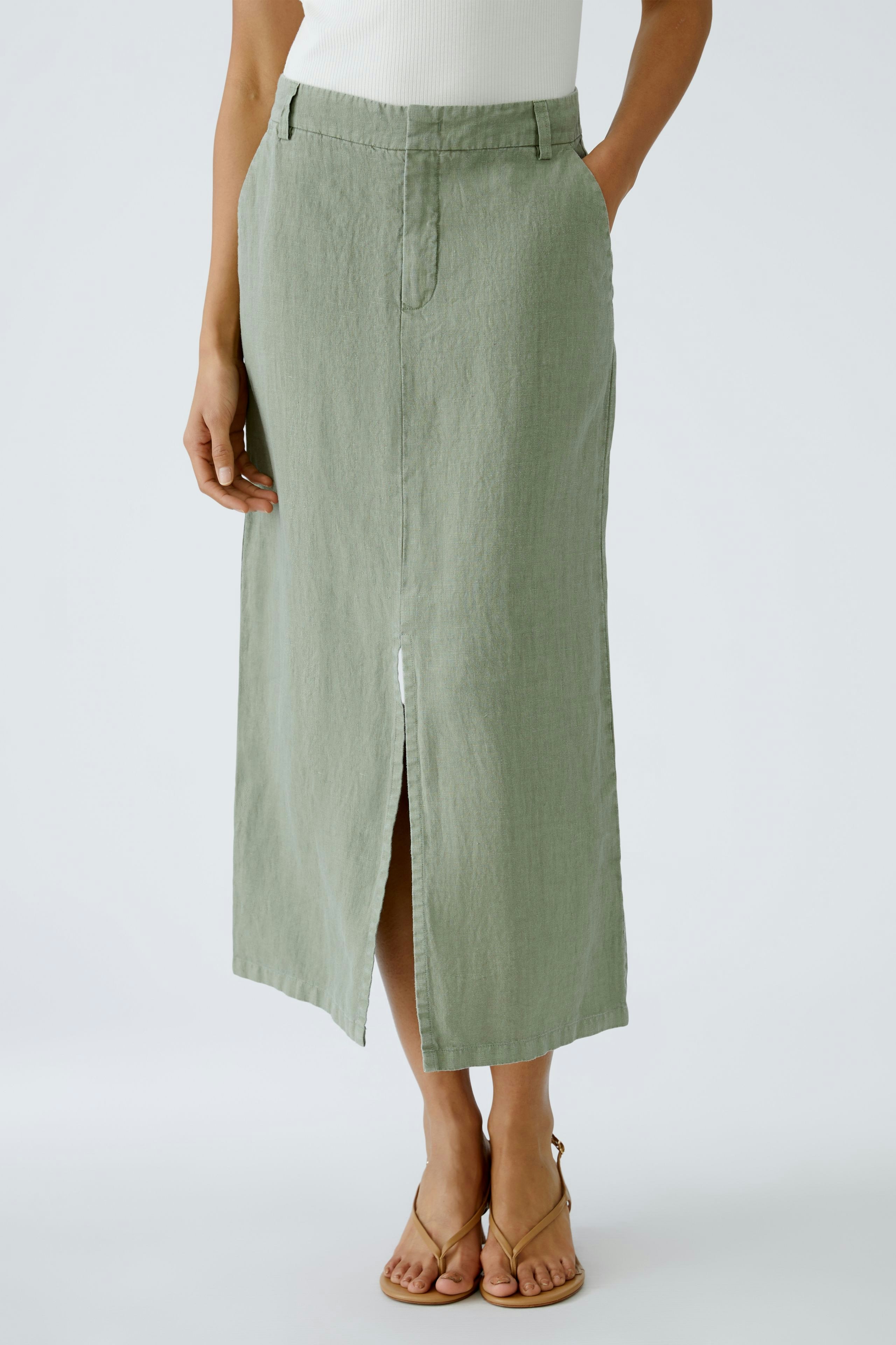 Chic midi skirt: A woman in a light green midi skirt with a front slit, styled with sandals.