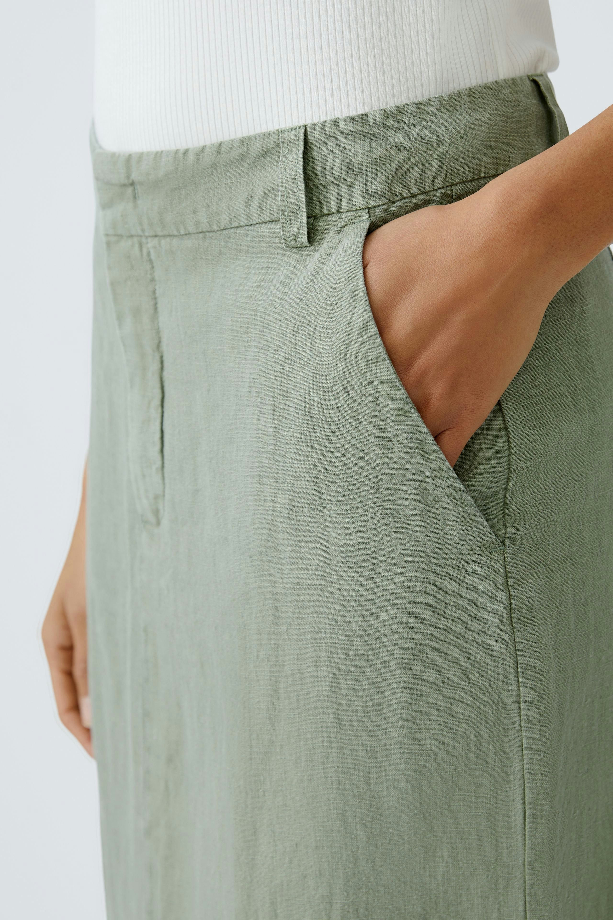 Elegant midi skirt: A woman showcases a light green midi skirt with pockets, perfect for any occasion.