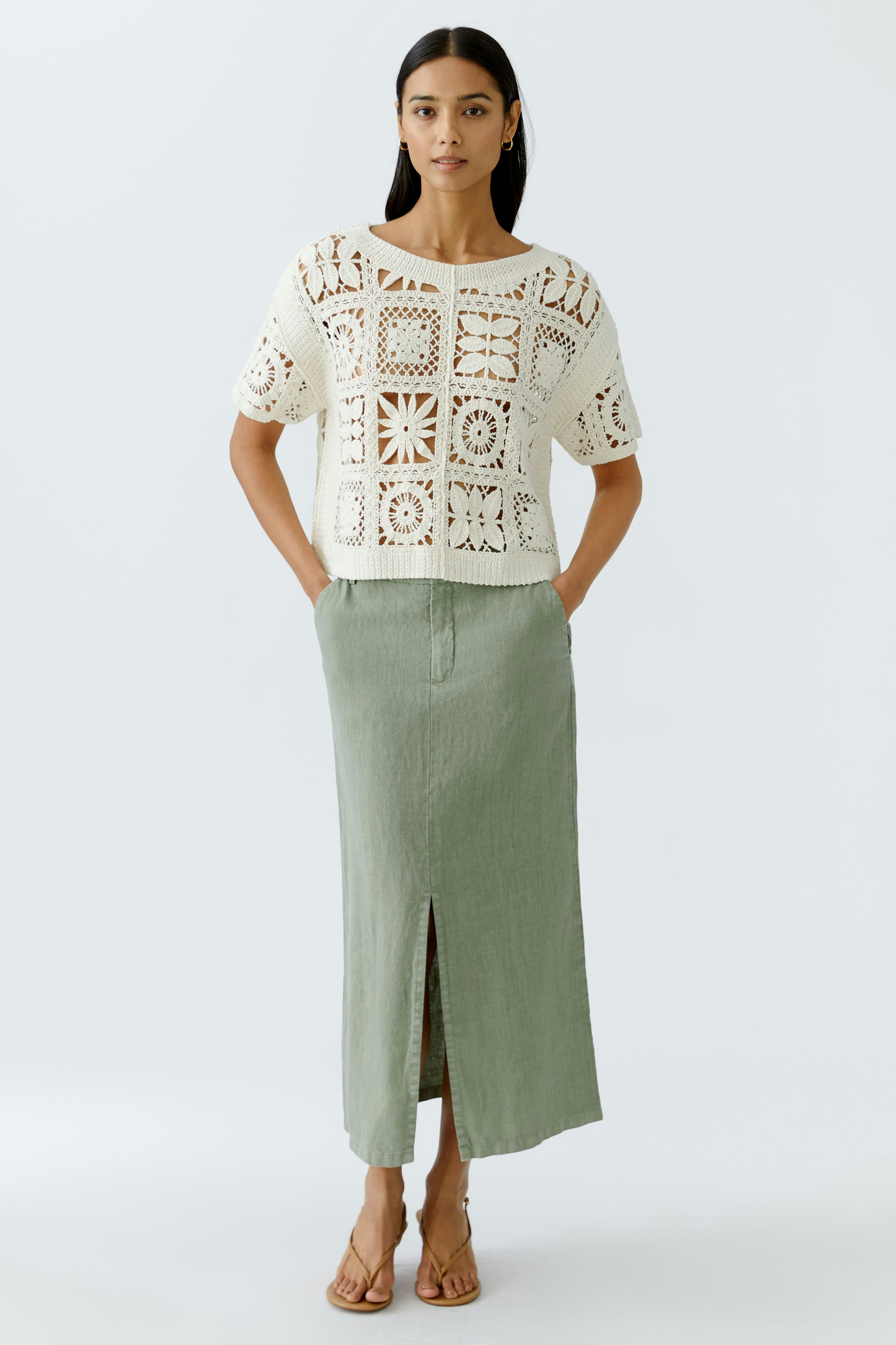 Elegant midirock: A woman in a light green midiskirt with a front slit, paired with a stylish top.