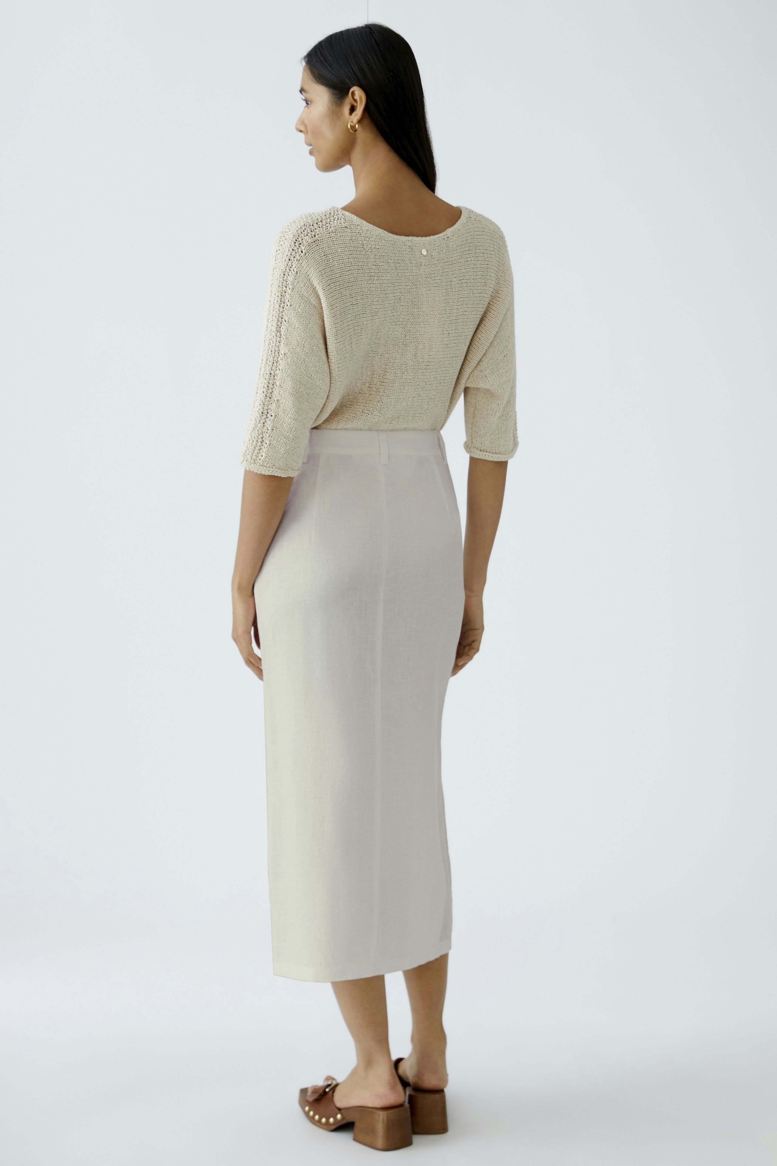 Eleganter Midirock: Frau in einem hellen, fließenden Midirock mit schlichter Eleganz von hinten.