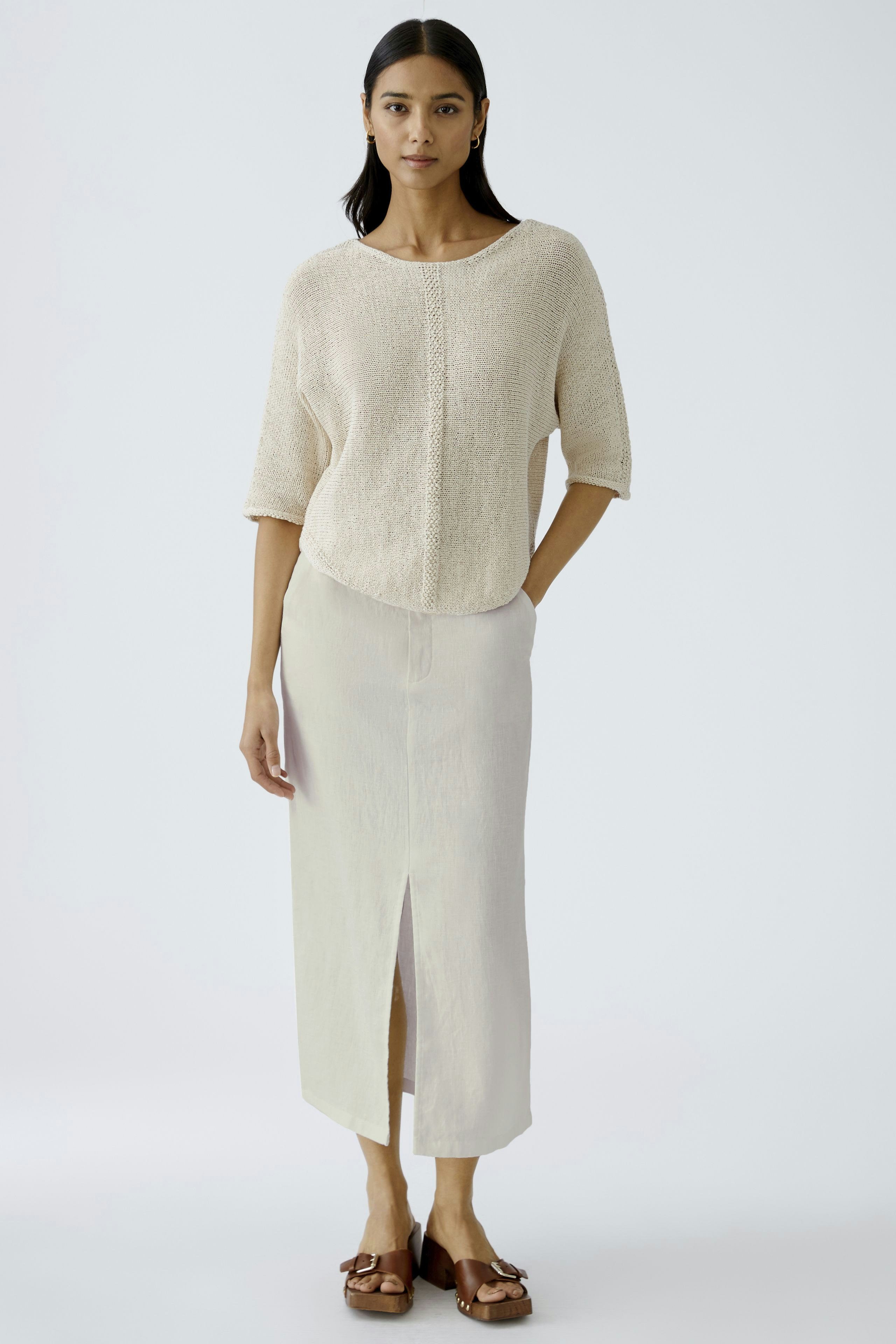 Eleganter Midirock: Frau in hellem, schlichten Midirock mit Schlitz, kombiniert mit einem lässigen Oberteil.