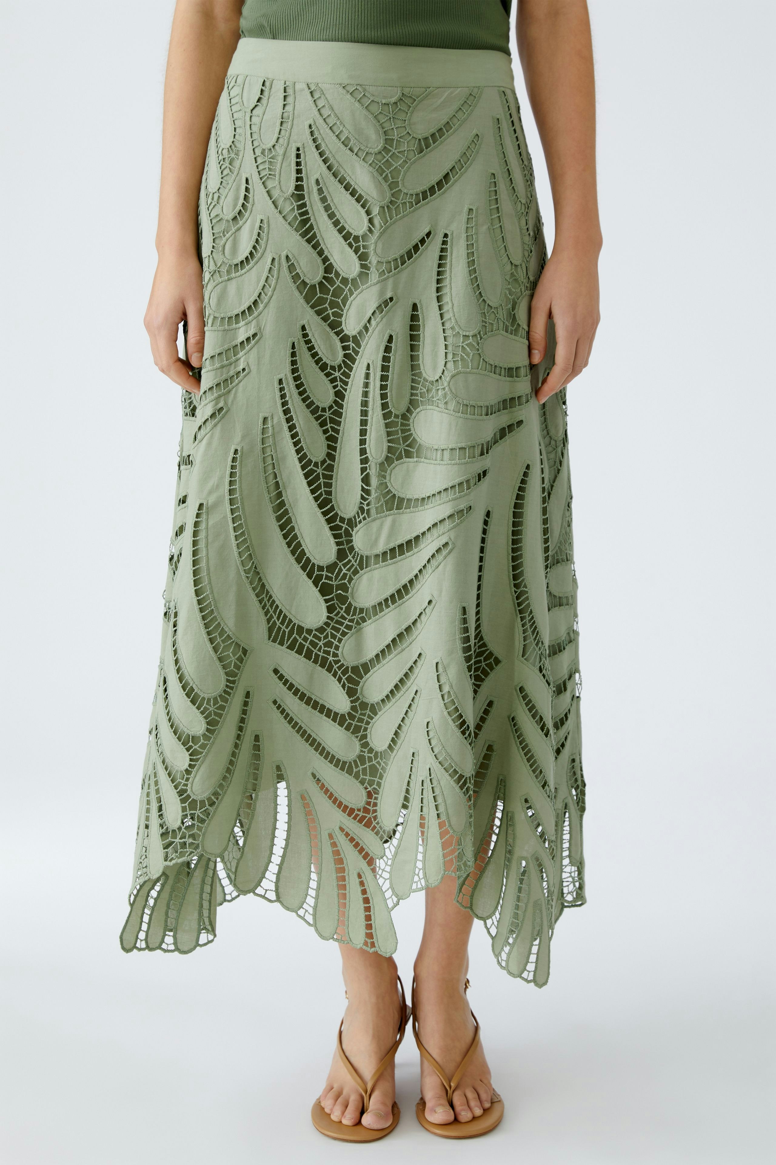 Elegant A-line skirt: Woman in a green skirt with intricate cut-out details, perfect for summer styling.