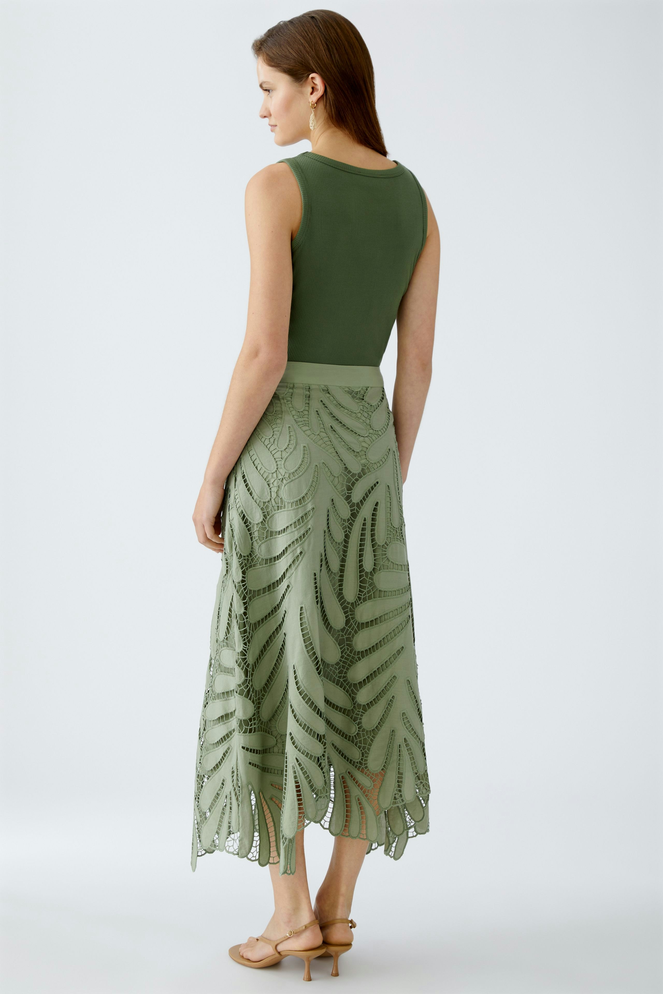 Elegant A-line skirt: Woman in a green skirt with intricate lace detailing, showcasing a stylish silhouette.