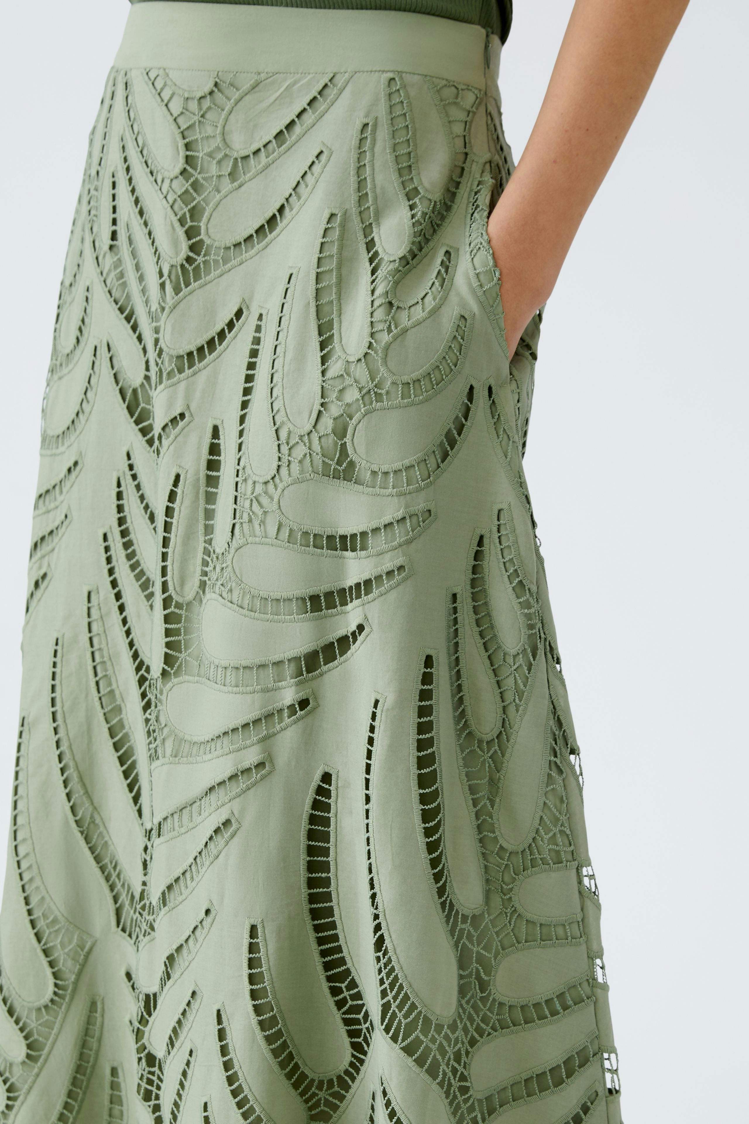 Elegant A-line skirt: A woman showcases a green skirt with intricate cut-out designs.