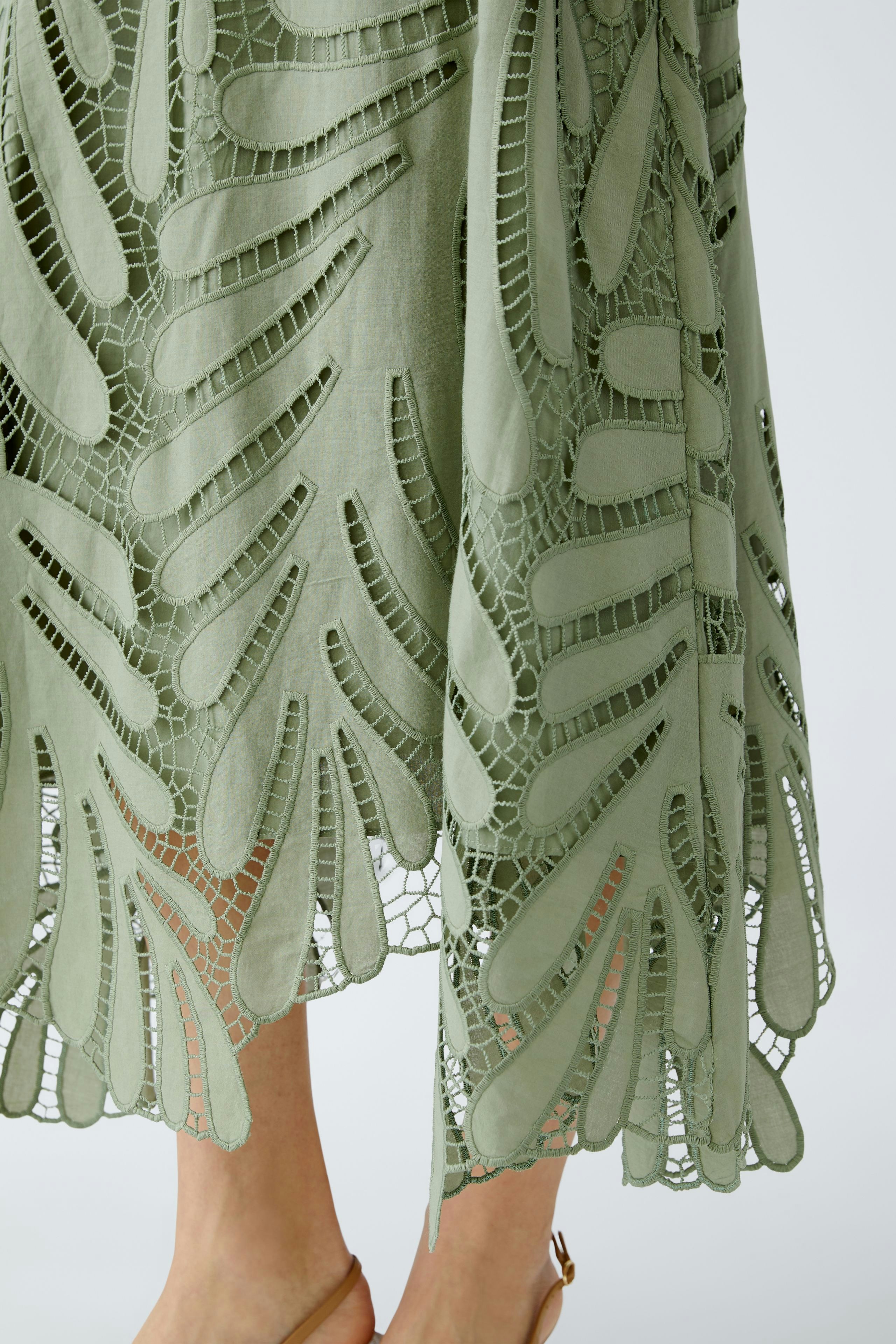 Elegant A-line skirt: A woman showcases a light green skirt with intricate cut-out details.