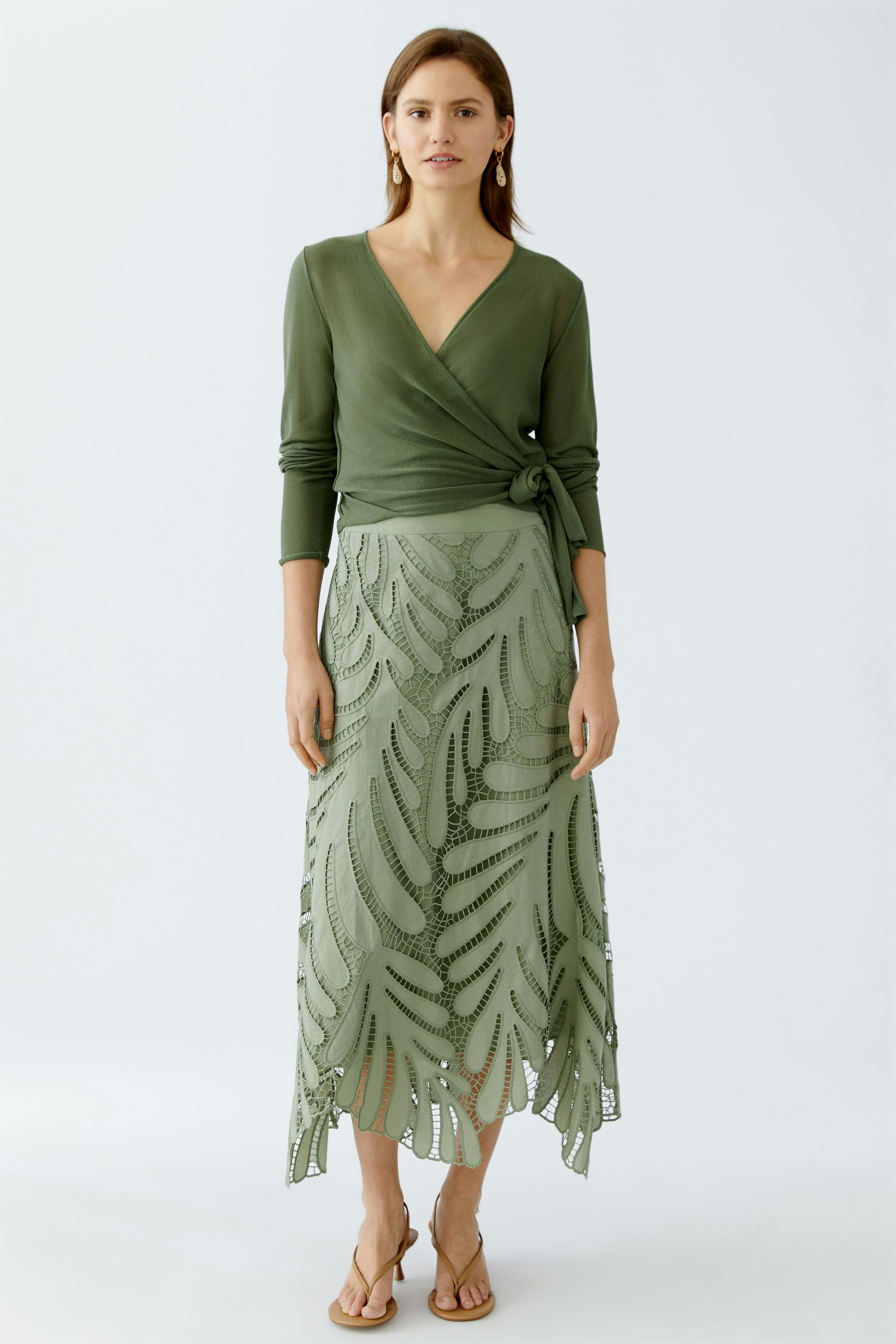 Elegant A-line skirt: Woman in a green skirt with intricate leaf patterns, paired with a stylish wrap top.