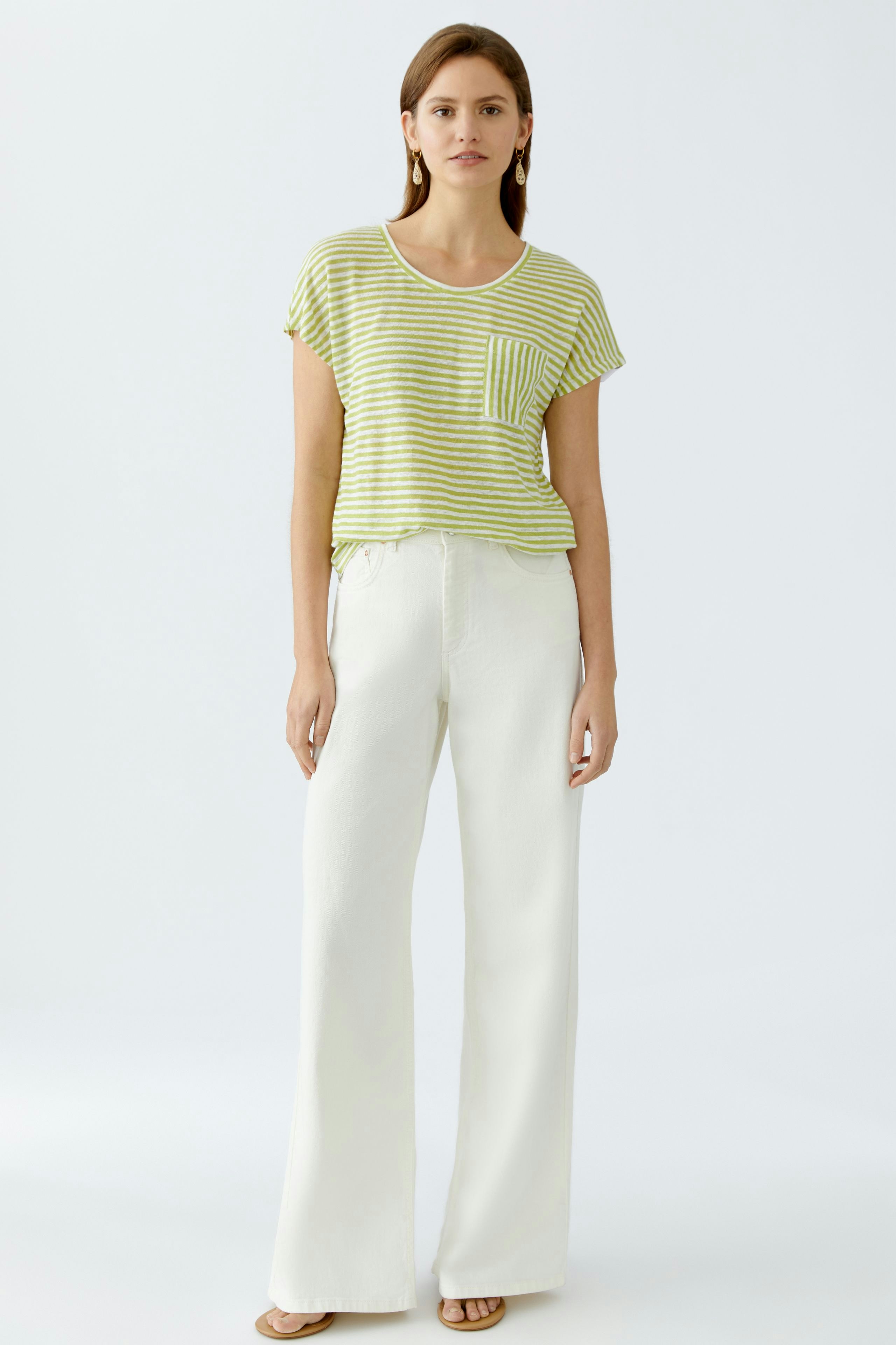 Lässiges Damen-T-Shirt: Frau in gestreiftem Shirt mit Brusttasche und lockeren, weißen Hosen.