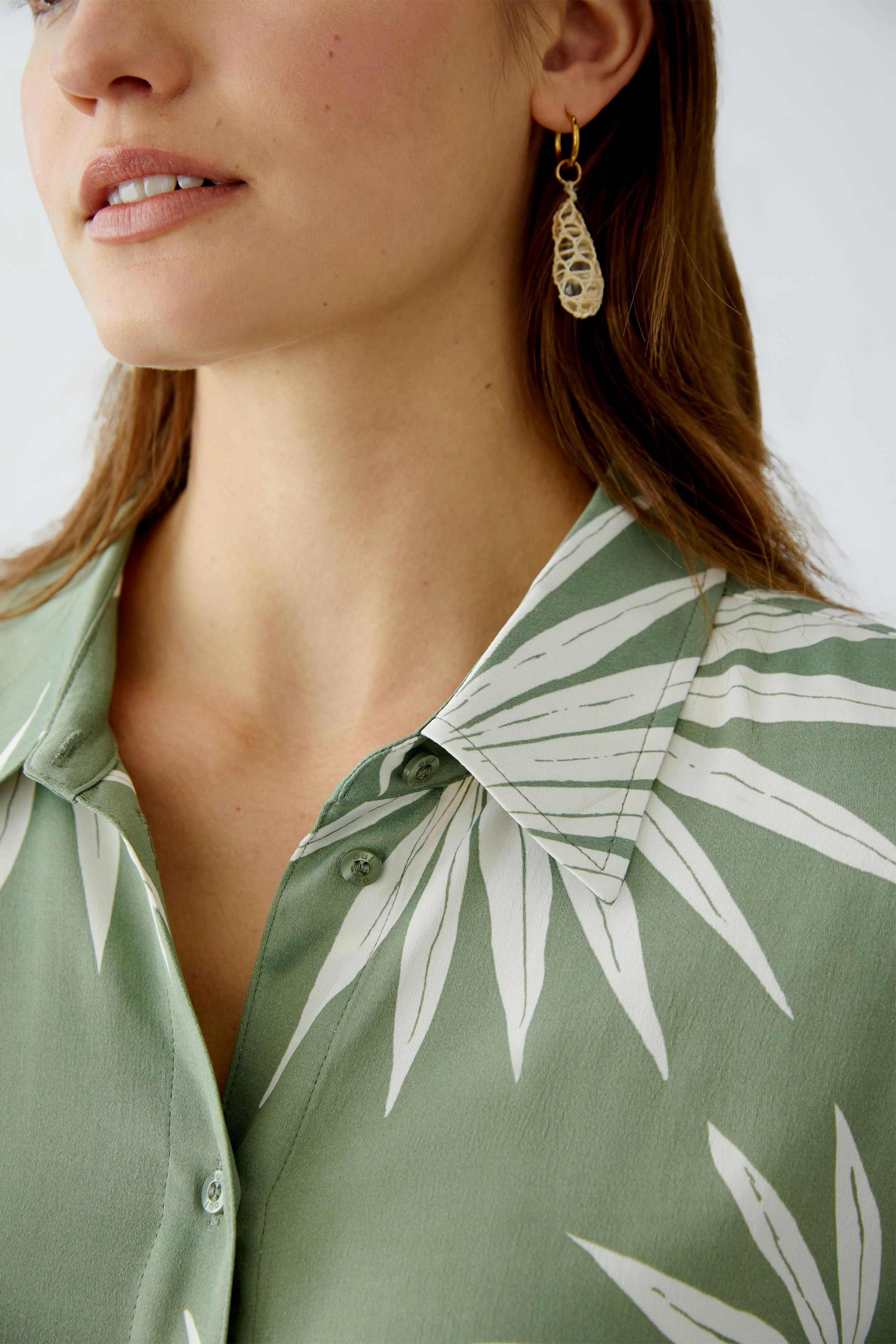 Stylish women's blouse in green with leaf print, featuring a classic collar and elegant design.