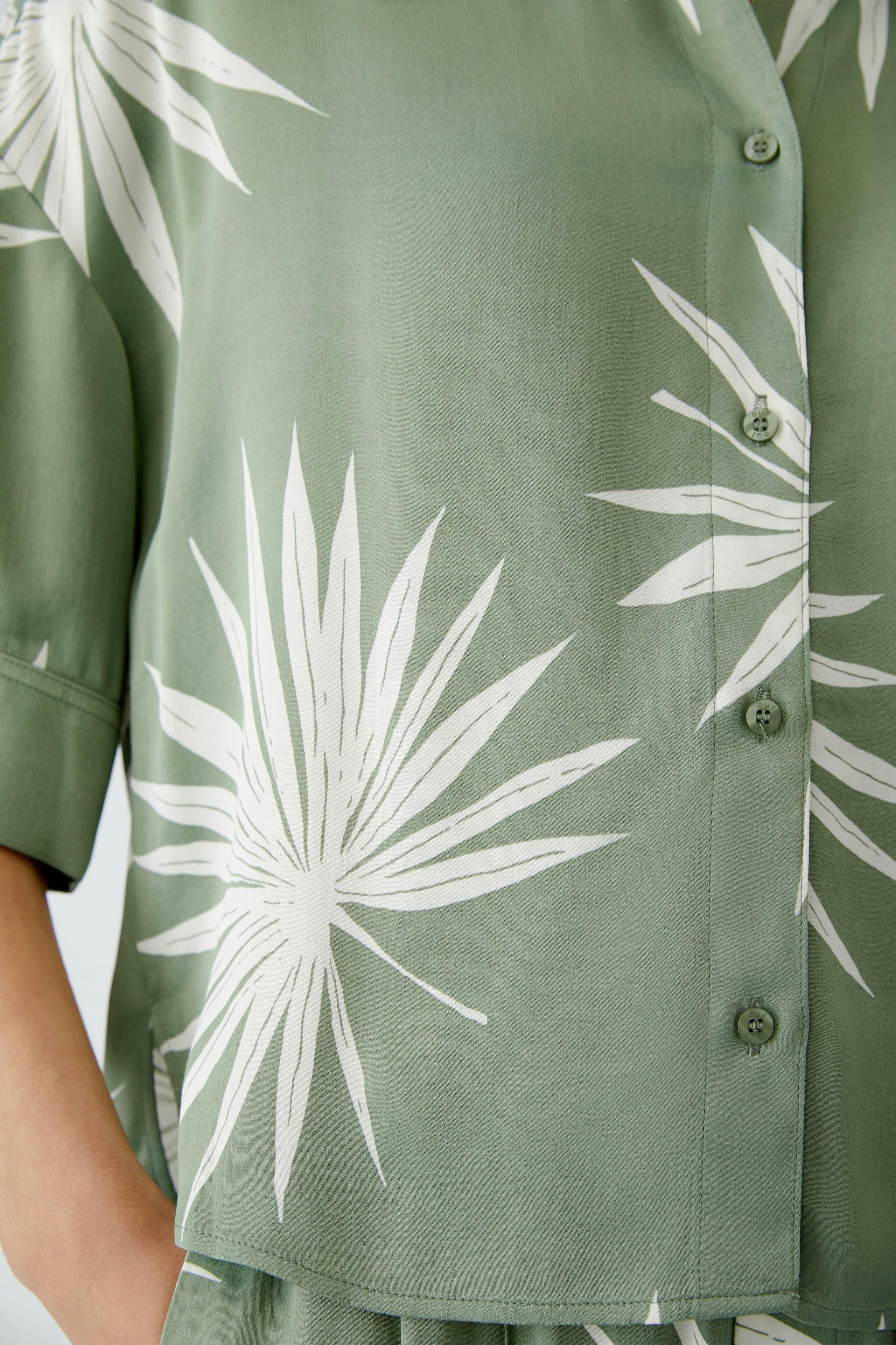 Stylish women's blouse in green with white leaf print, featuring a relaxed fit and button closure.
