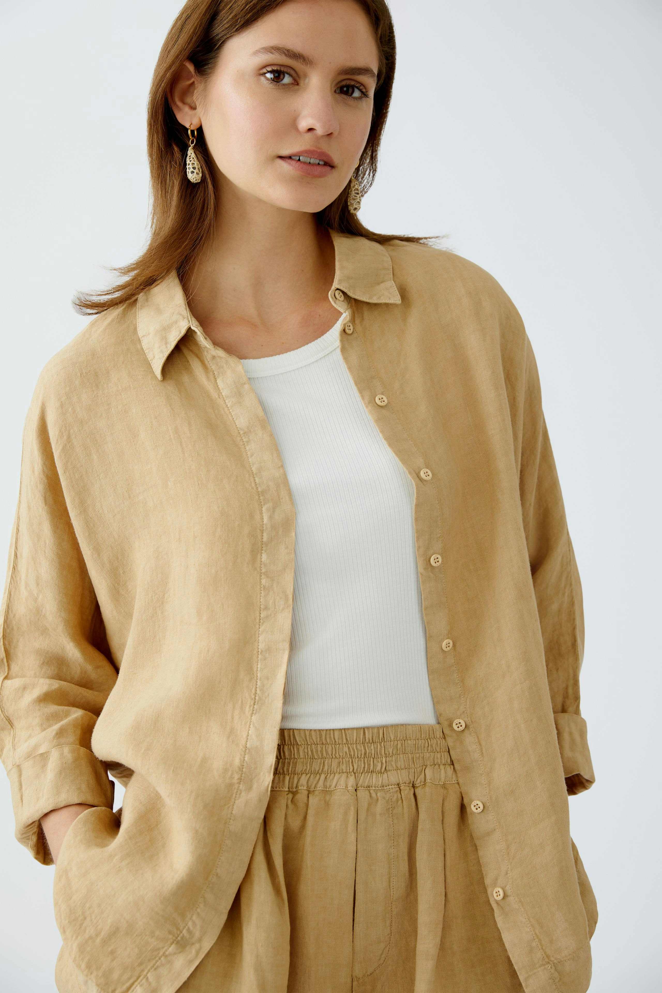 Bequeme Damen-Bluse: Frau in einer leichten, sandfarbenen Bluse mit lässigem Schnitt und Knopfleiste.