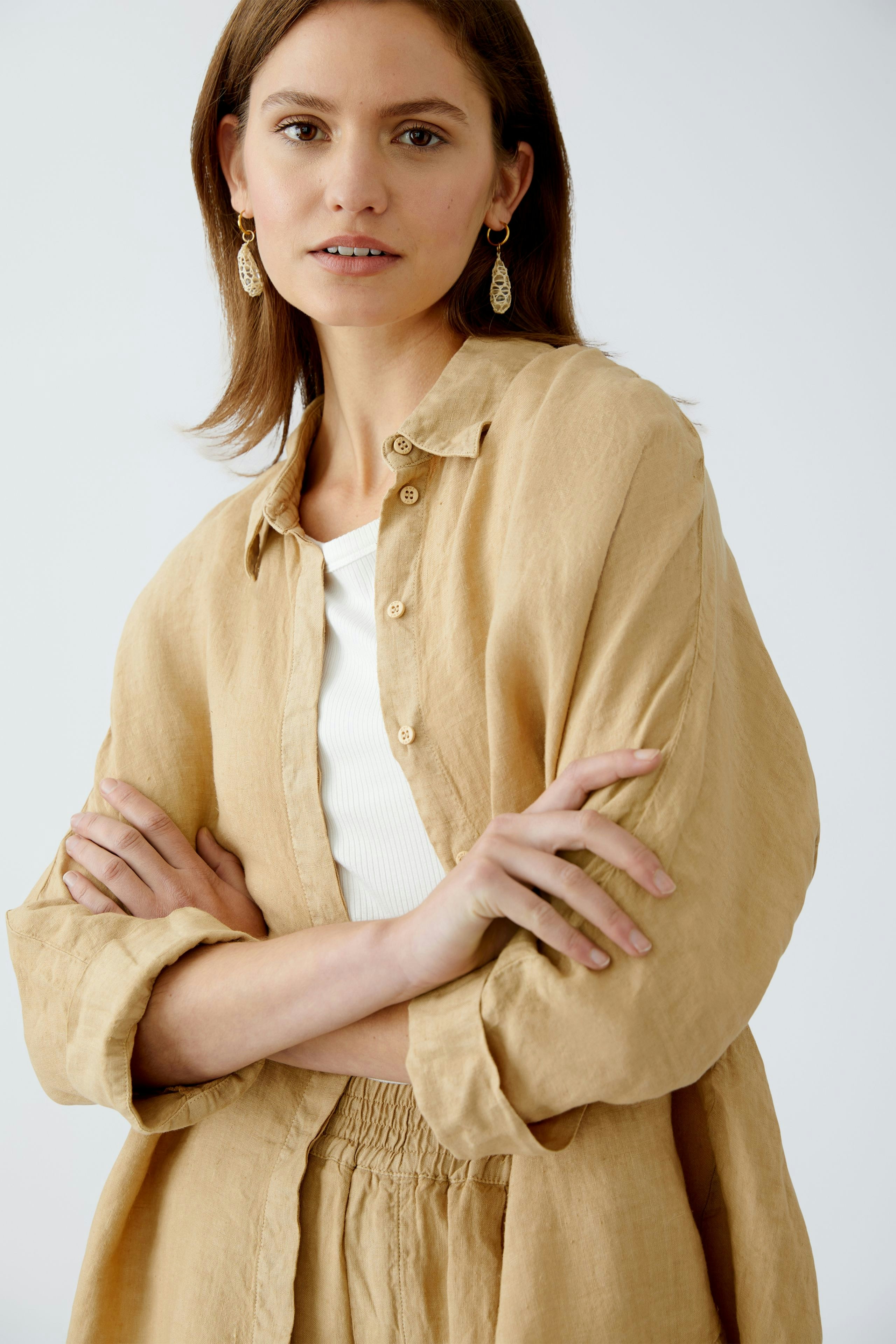 Bequeme Damen-Bluse: Frau in einer leichten, sandfarbenen Bluse mit Knöpfen und lässigem Look.