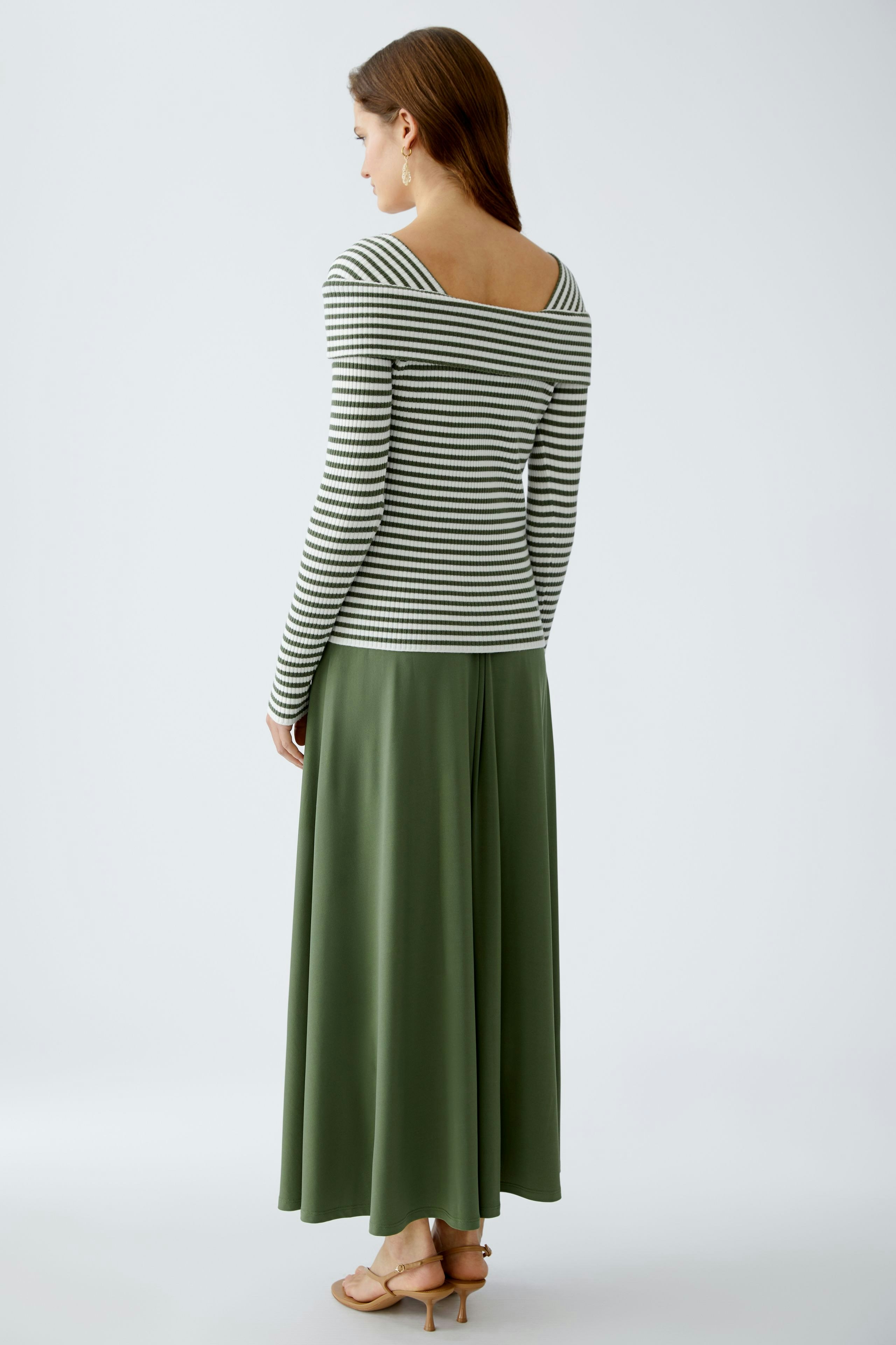 Damen-Pullover: Frau in gestreiftem Pullover mit weitem Rückenausschnitt und grünem Rock.