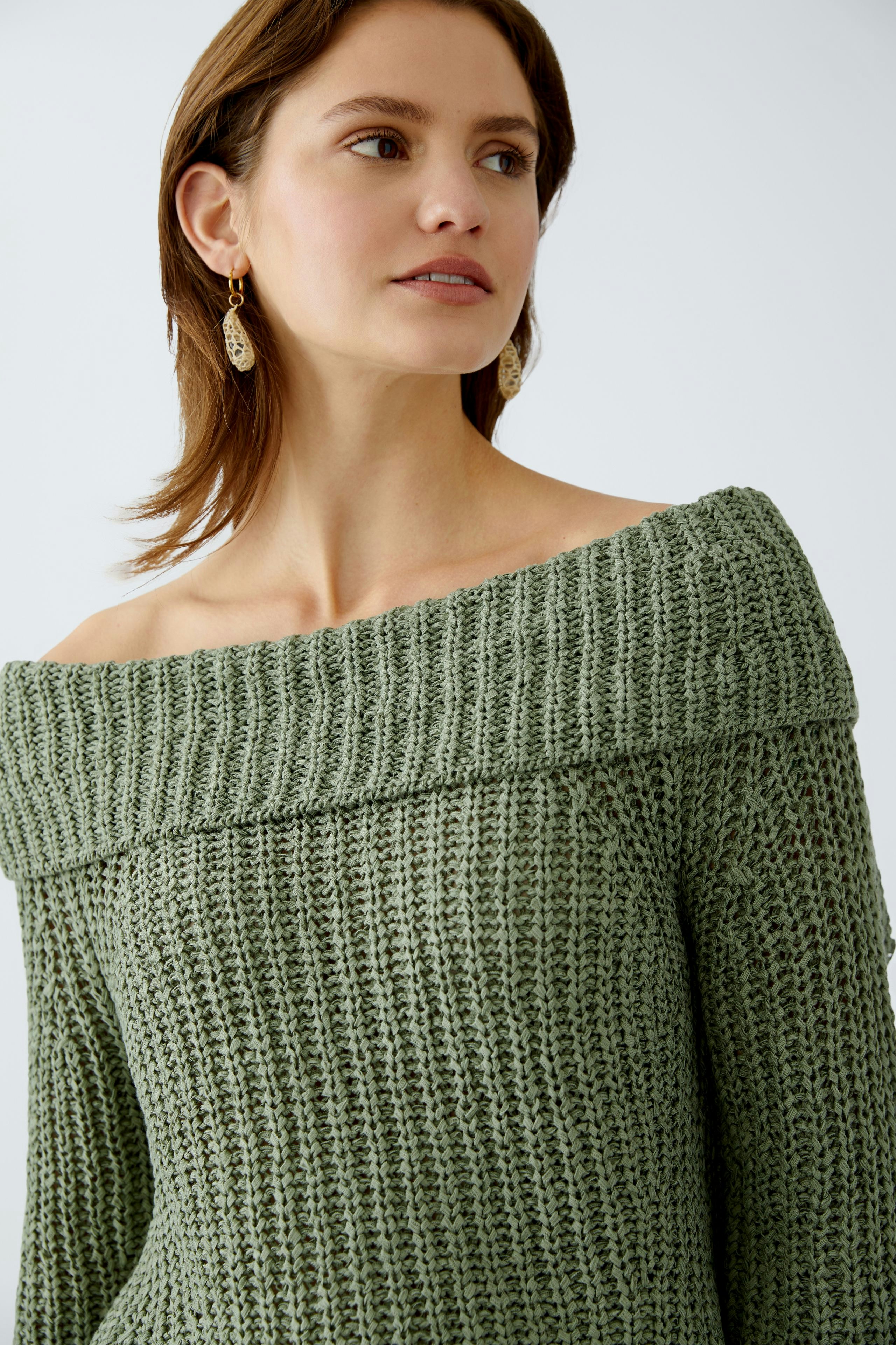 Stylish women's pullover: A woman in a green off-shoulder knit pullover, exuding elegance.