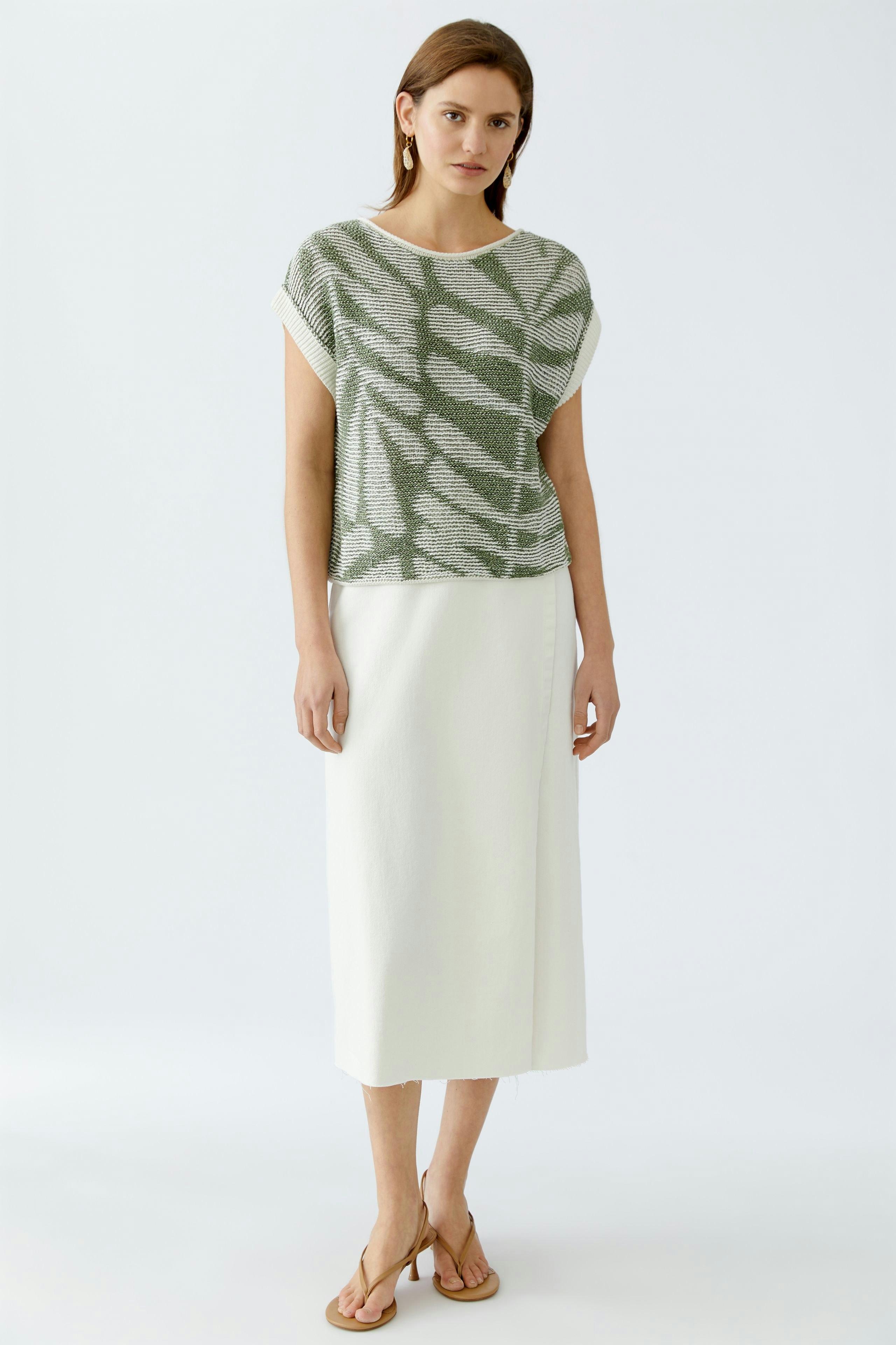 Stylish women's pullover: A woman in a green patterned pullover paired with a white skirt.