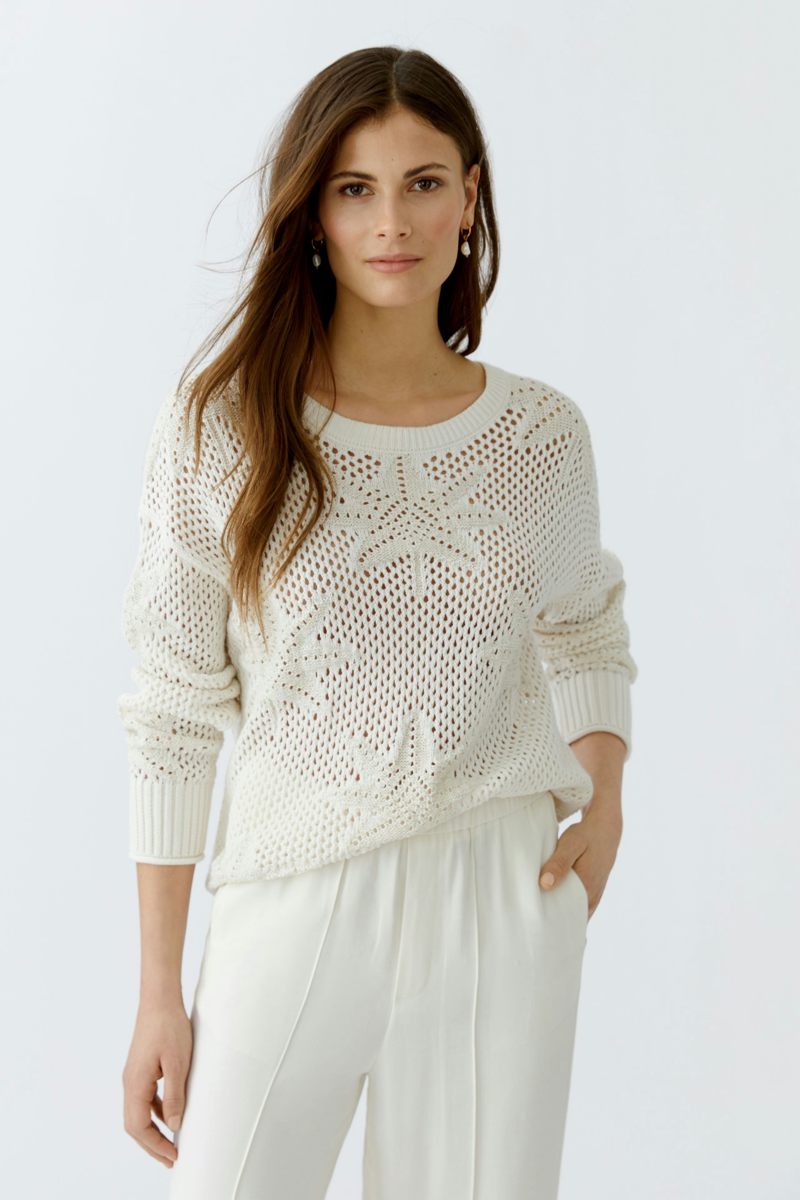 Damen-Pullover: Frau in einem weißen, luftigen Strickpullover mit feinem Muster und lässigem Schnitt.