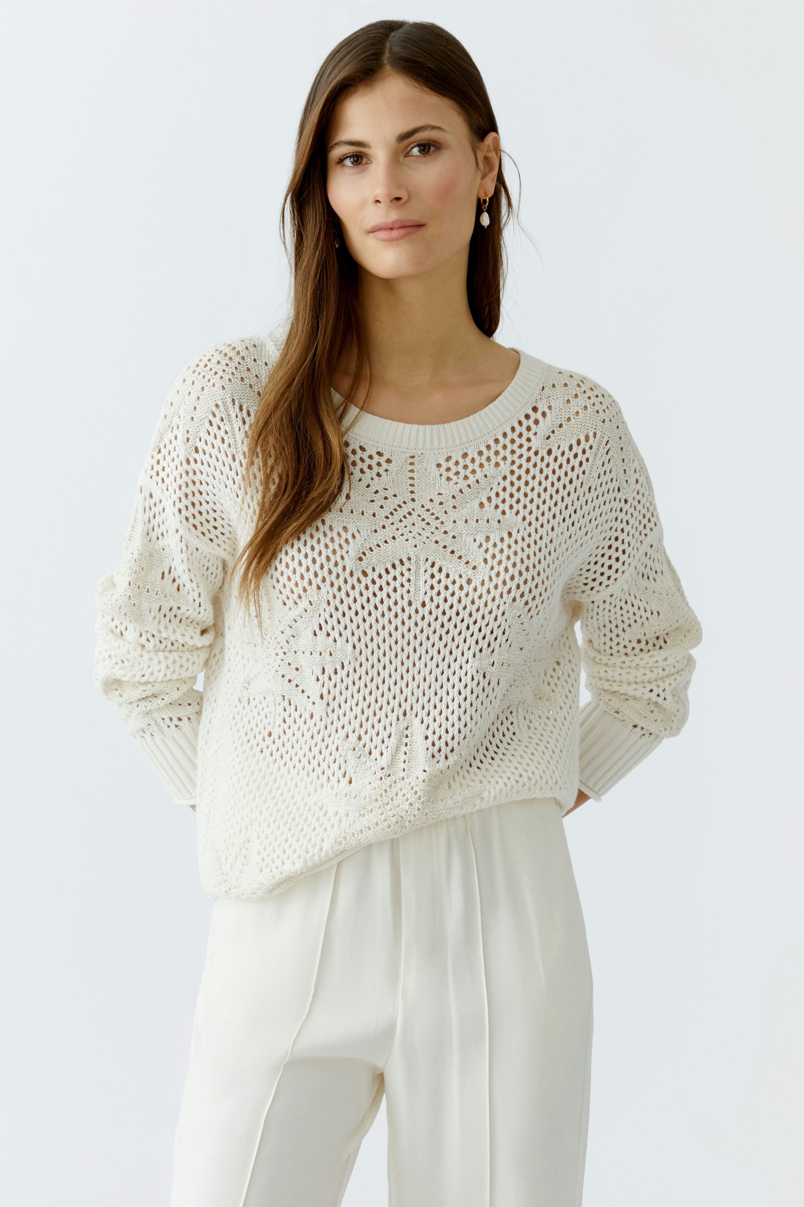 Damen-Pullover: Frau in einem weißen, luftigen Strickpullover mit floralem Muster und lässiger Passform.