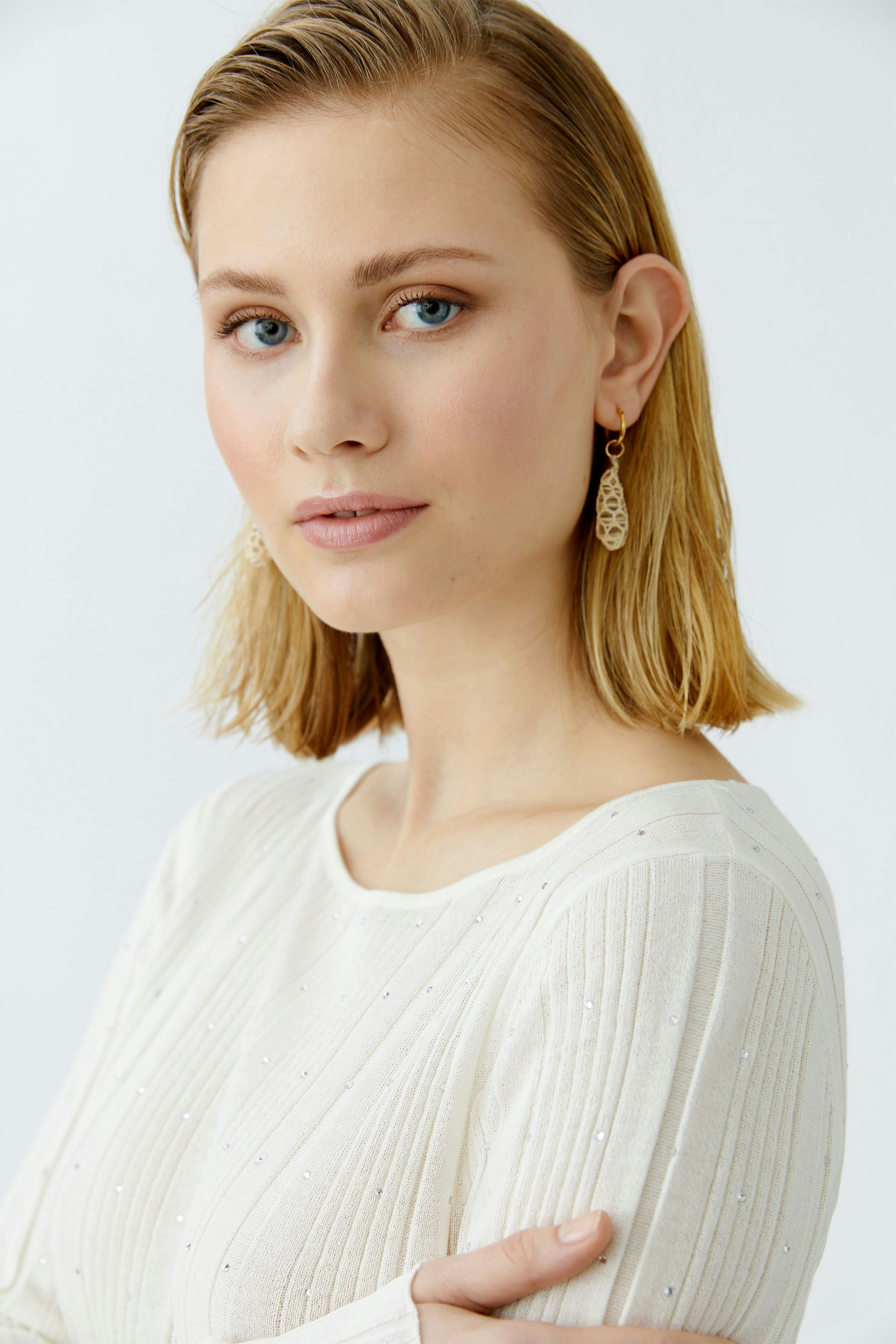 Eleganter Damen-Pullover: Frau mit kurzem, blondem Haar trägt einen cremefarbenen, strukturierten Pullover.