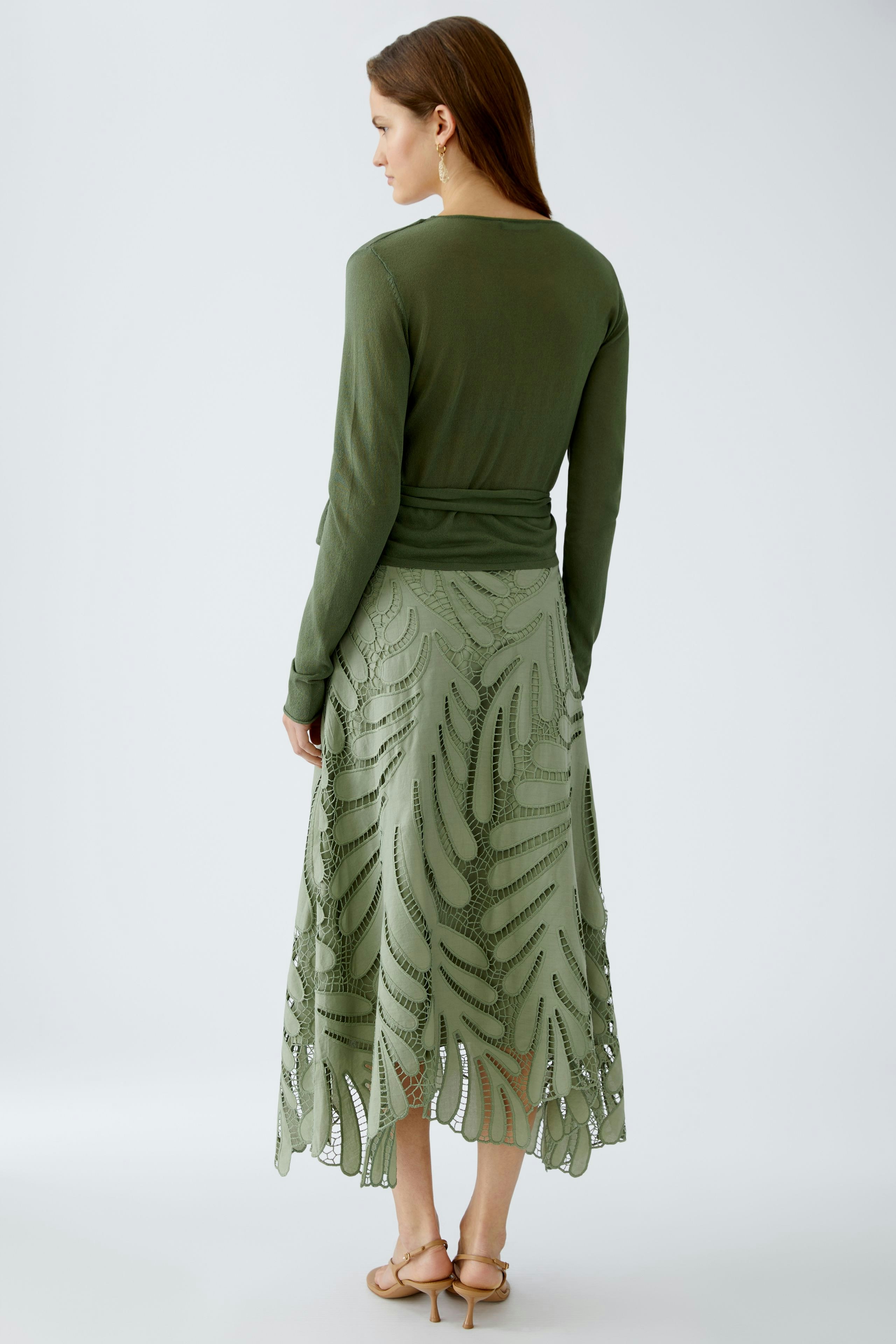 Elegante Damen-Strickjacke in Olivgrün, lässig kombiniert mit einem luftigen Rock.