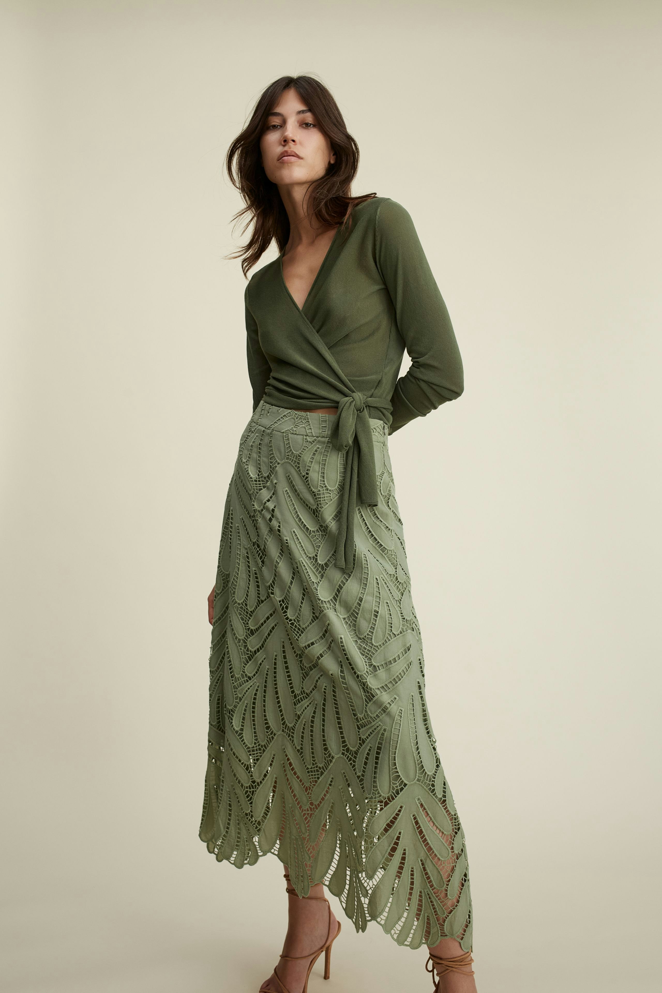 Elegante Damen-Strickjacke: Frau in olivgrüner Jacke mit Bindegürtel und passendem Rock.