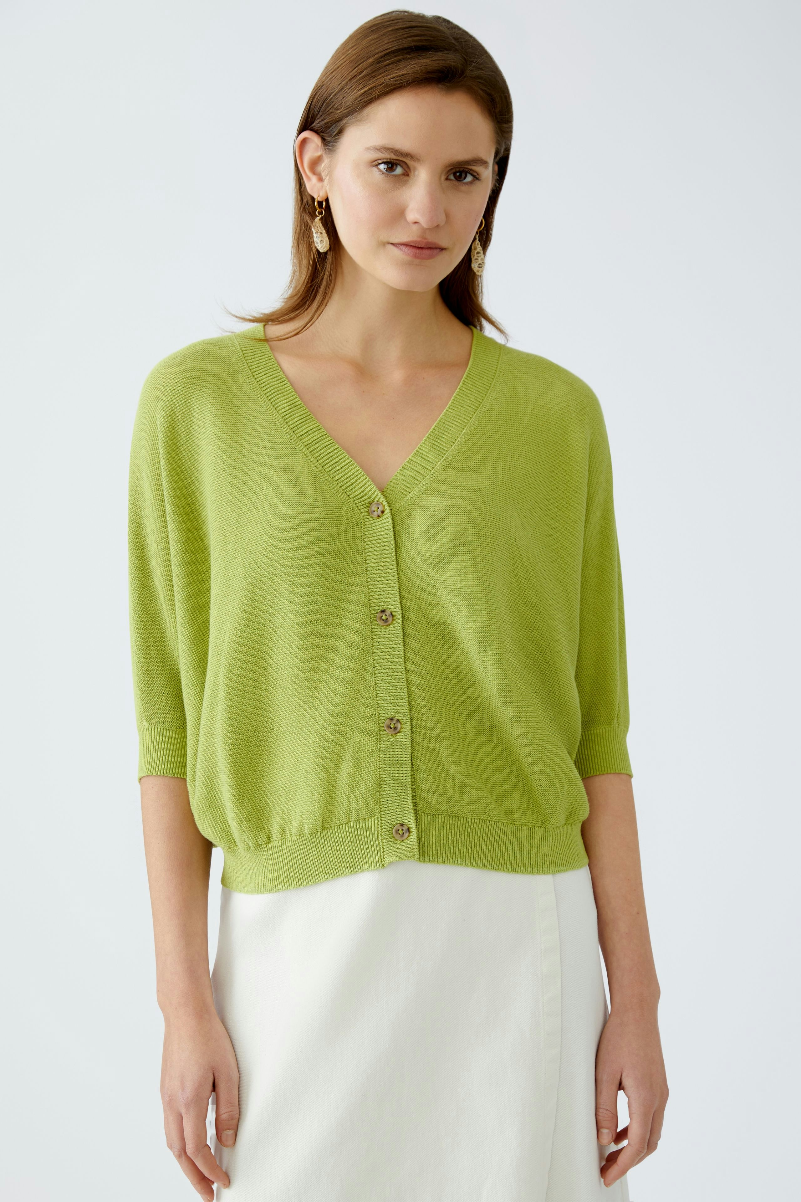 Stylish women's cardigan: A woman in a light green cardigan with buttons, perfect for layering.