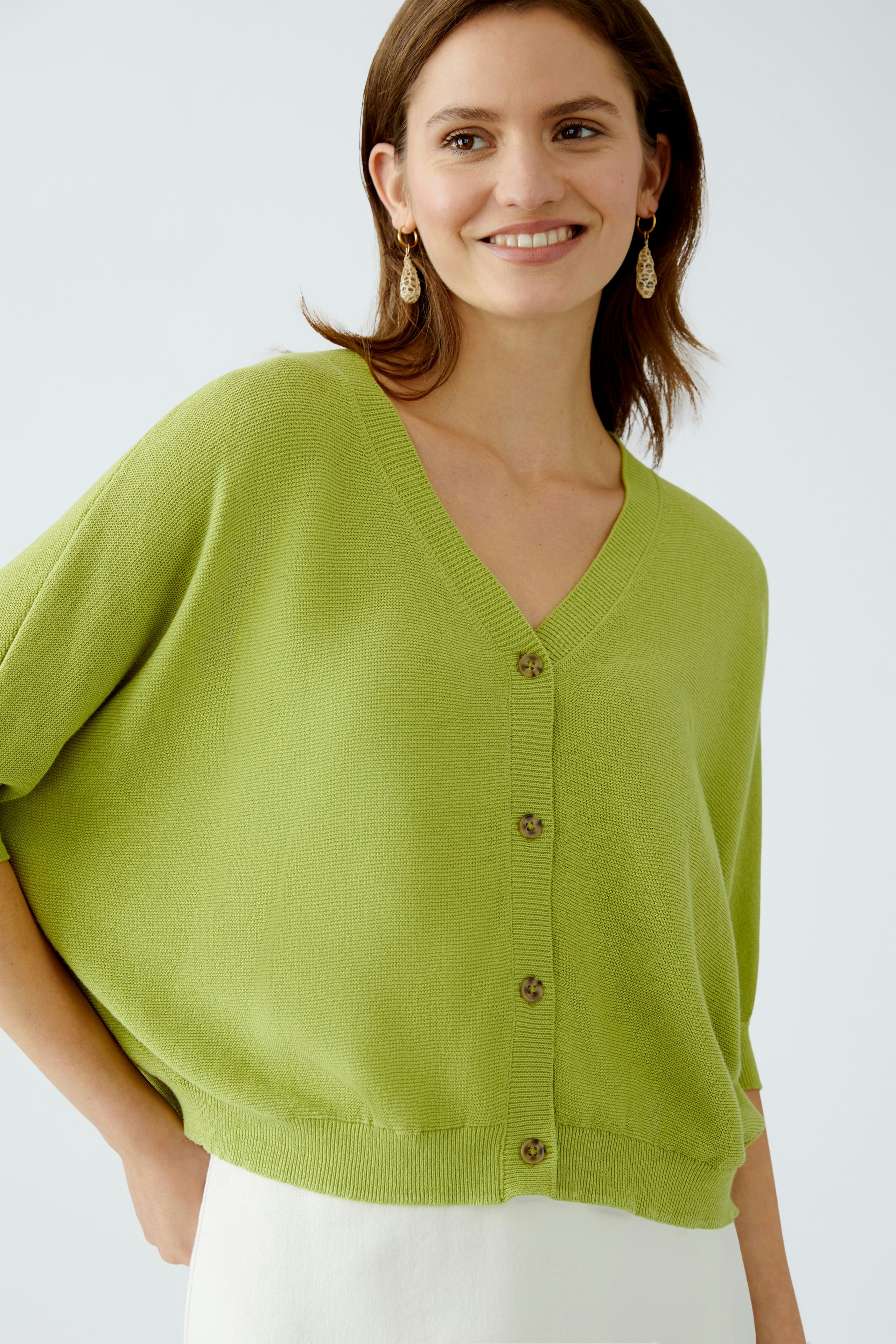 Stylish women's cardigan: A woman in a light green cardigan with buttons, exuding casual elegance.