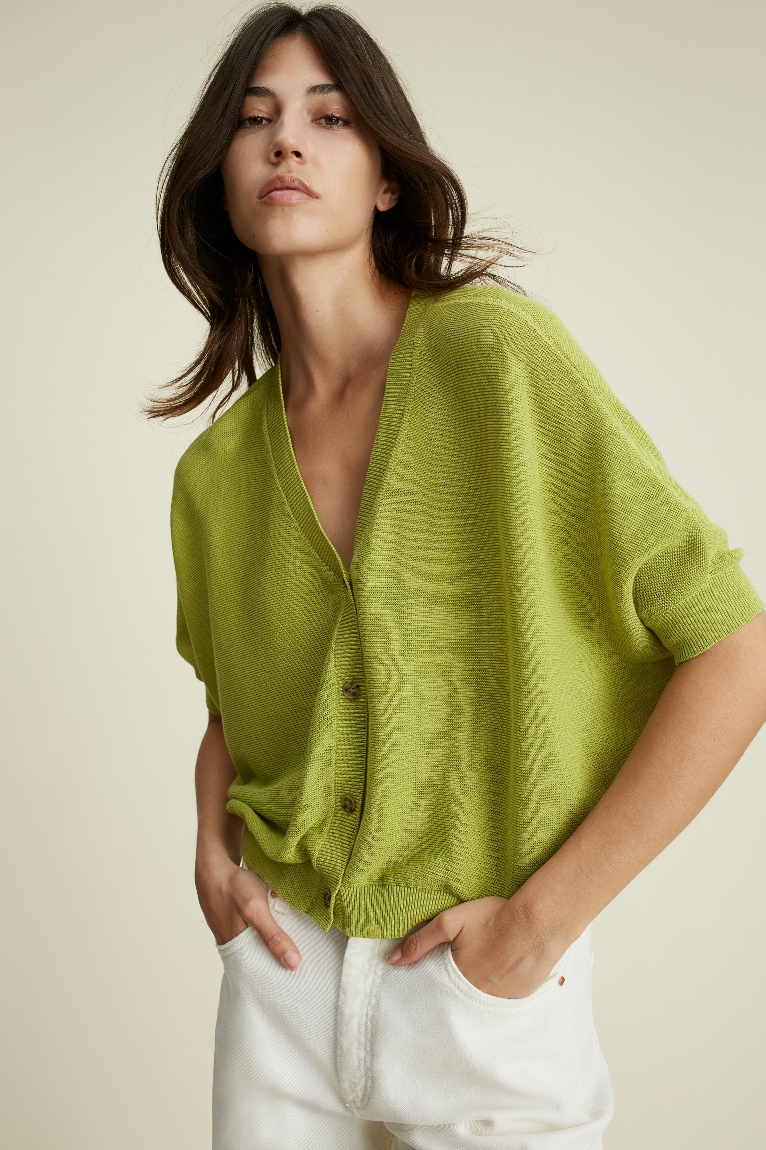 Stylish women's cardigan: A woman in a vibrant green cardigan with buttons, exuding casual elegance.