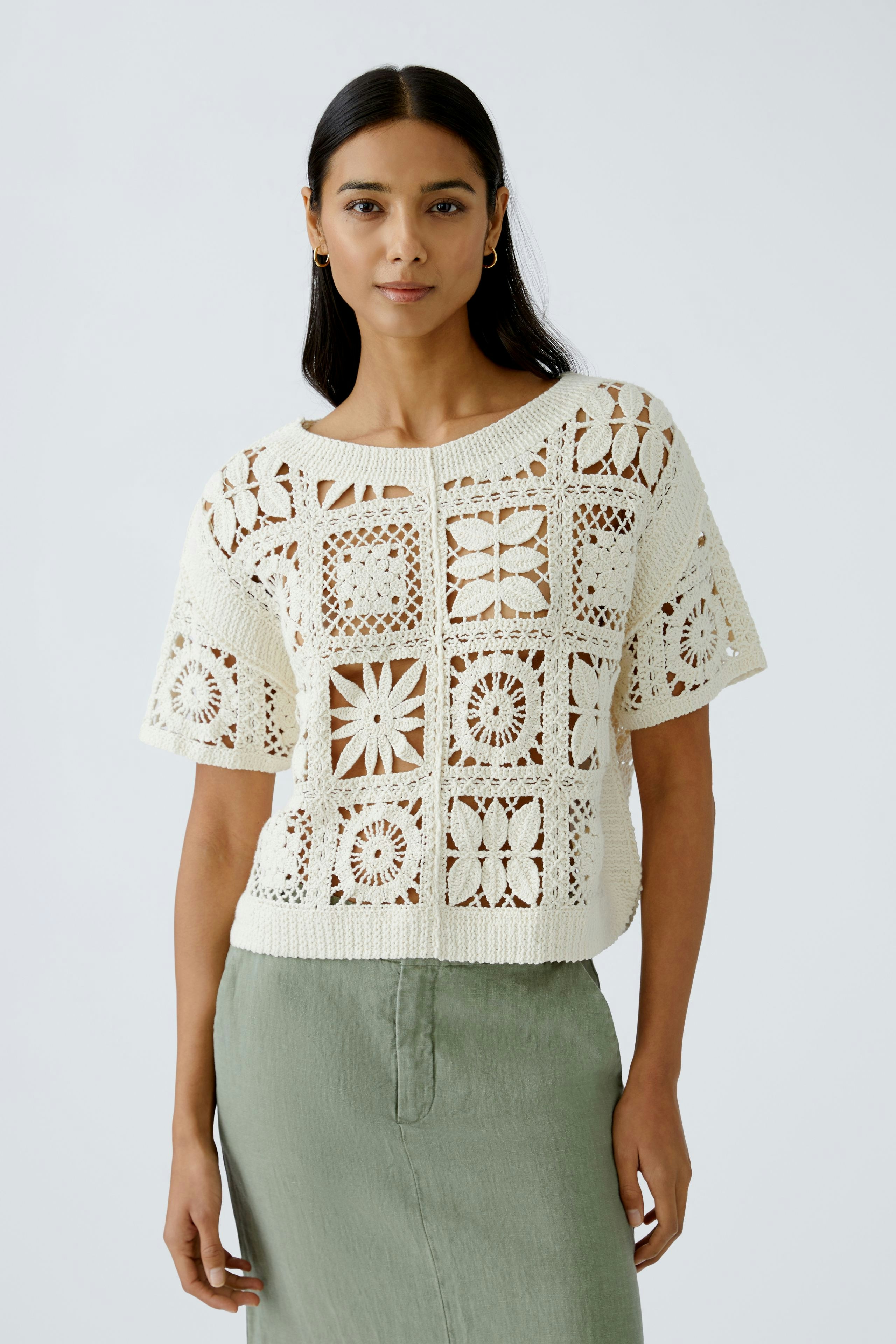 Stylish women's pullover: A woman in a cream crochet pullover with floral patterns, paired with a green skirt.