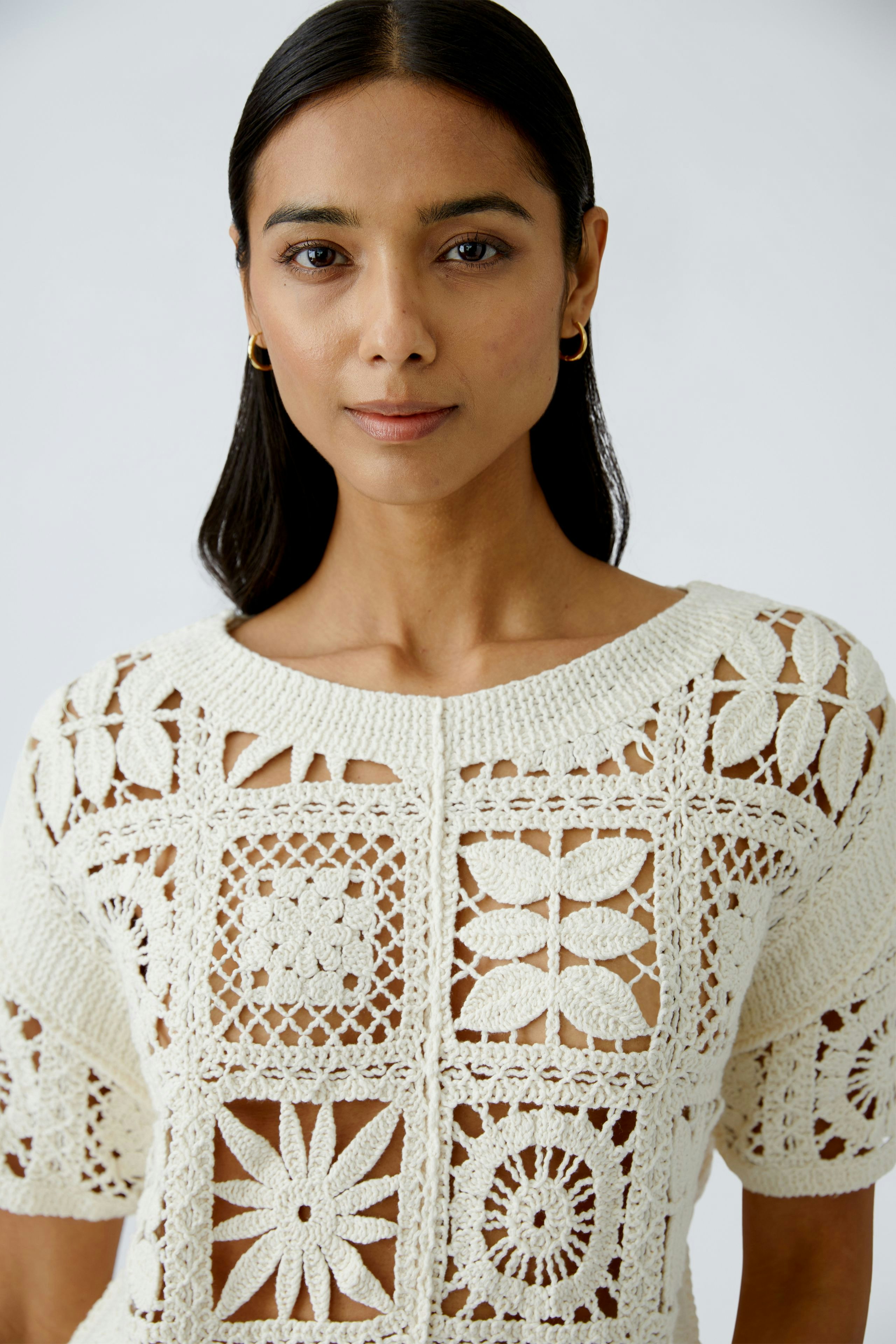 Stylish women's pullover: A woman in a cream crochet pullover with intricate patterns.