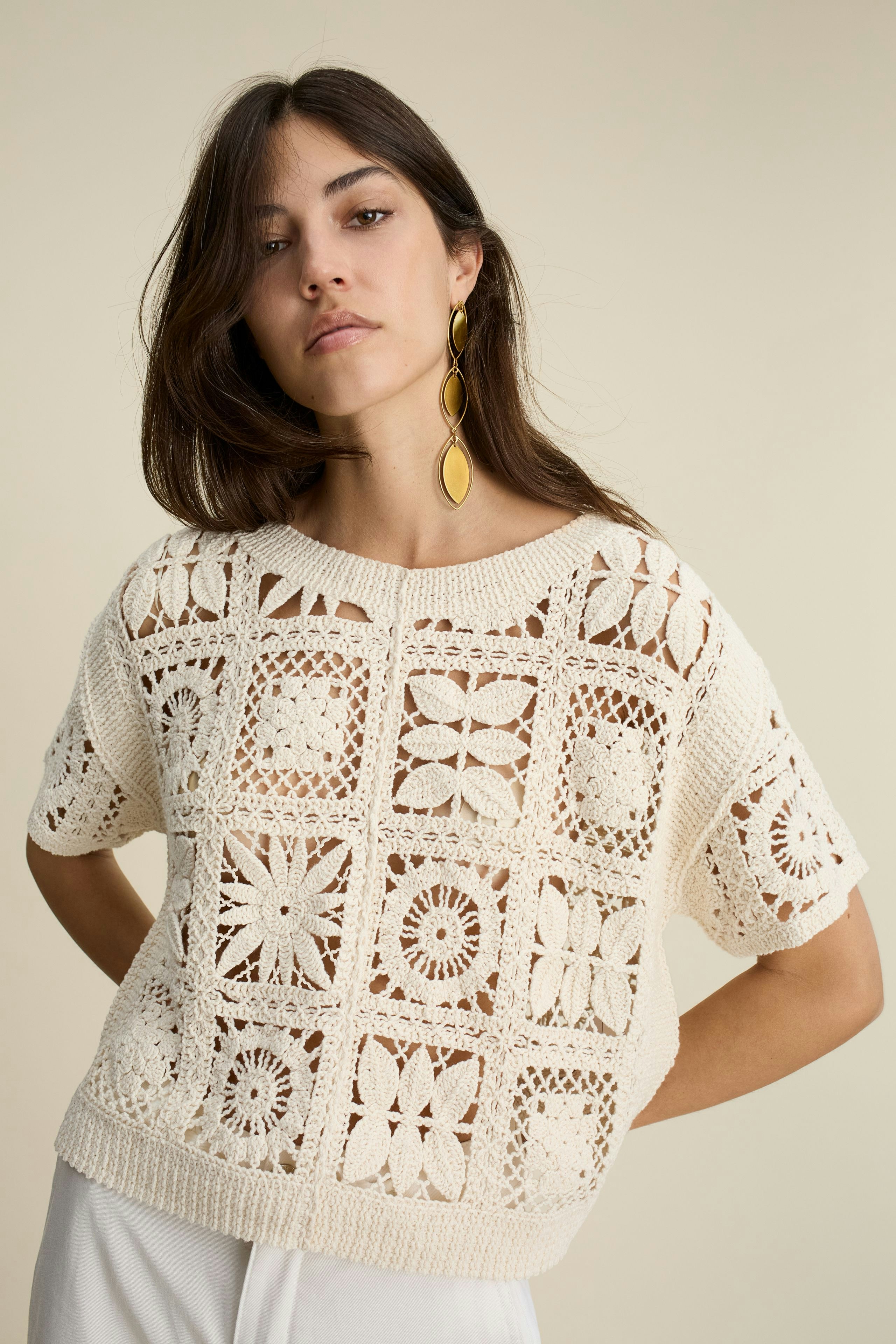 Stylish women's pullover: A woman in a cream crochet pullover with a relaxed fit and unique patterns.