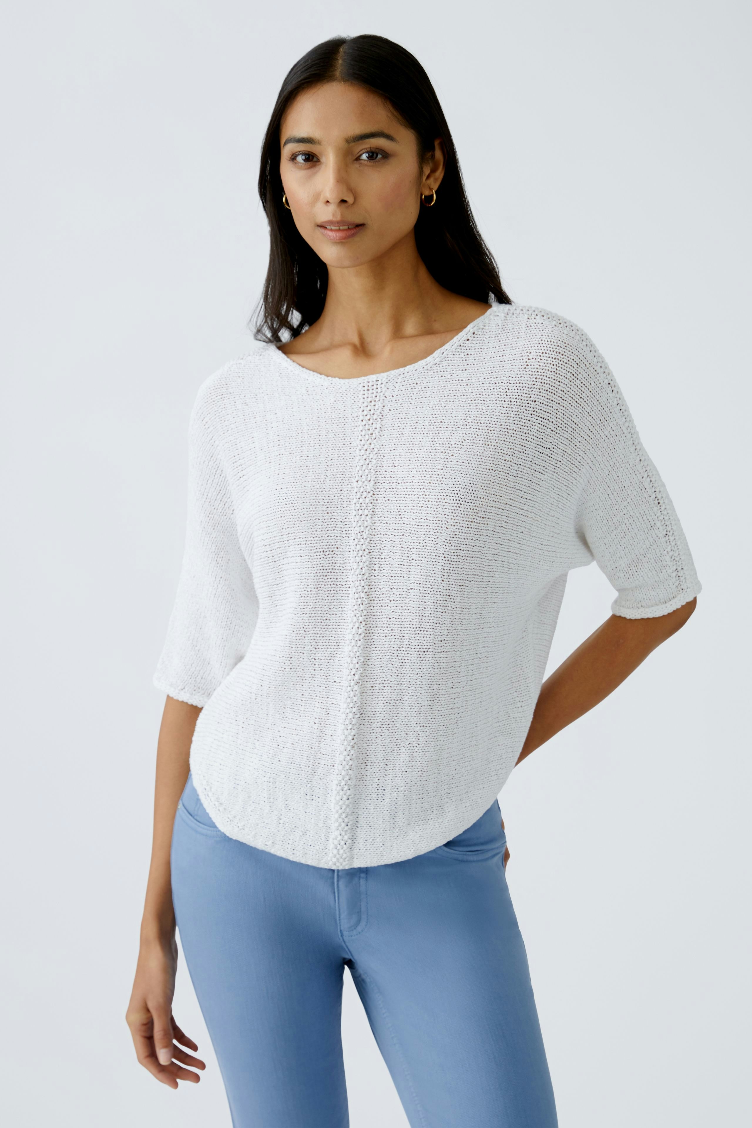 Eleganter Damen-Pullover: Frau in weißem, lässigem Strickpullover mit kurzen Ärmeln und Rundhalsausschnitt.