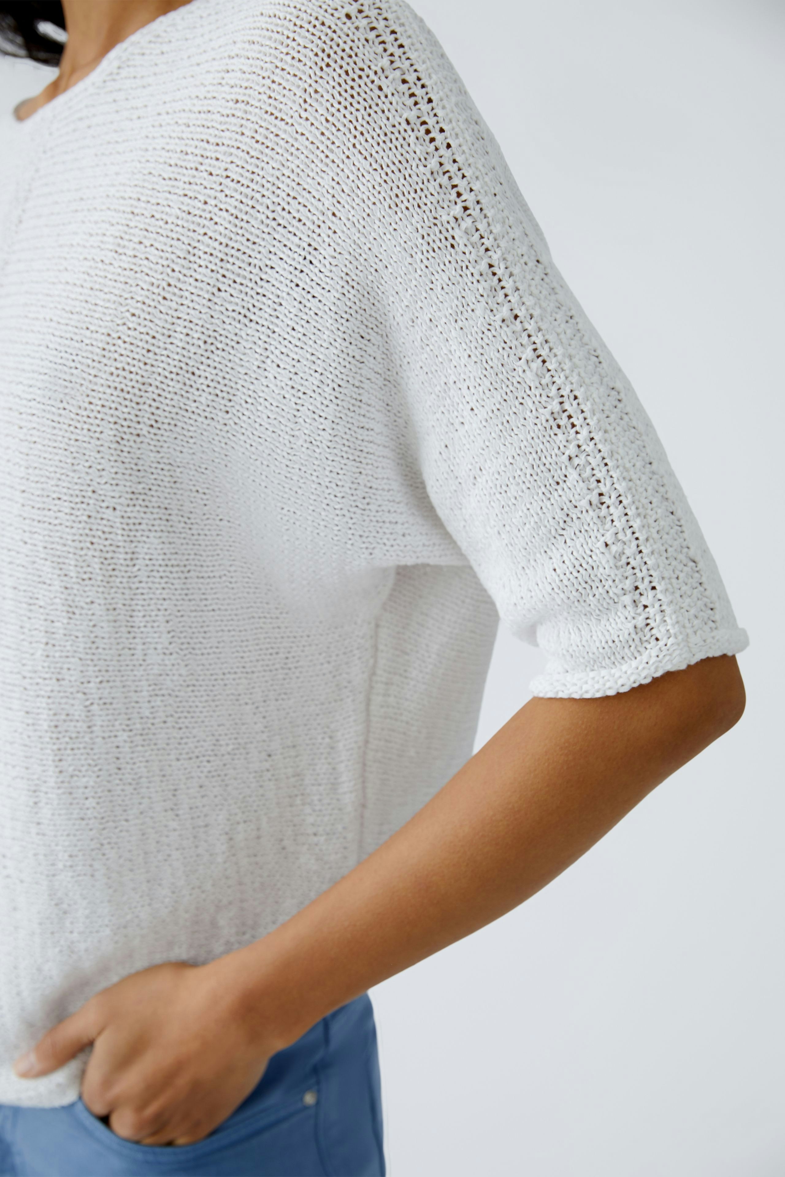 Eleganter Damen-Pullover: Frau in einem weißen, lässigen Strickpullover mit kurzen Ärmeln.