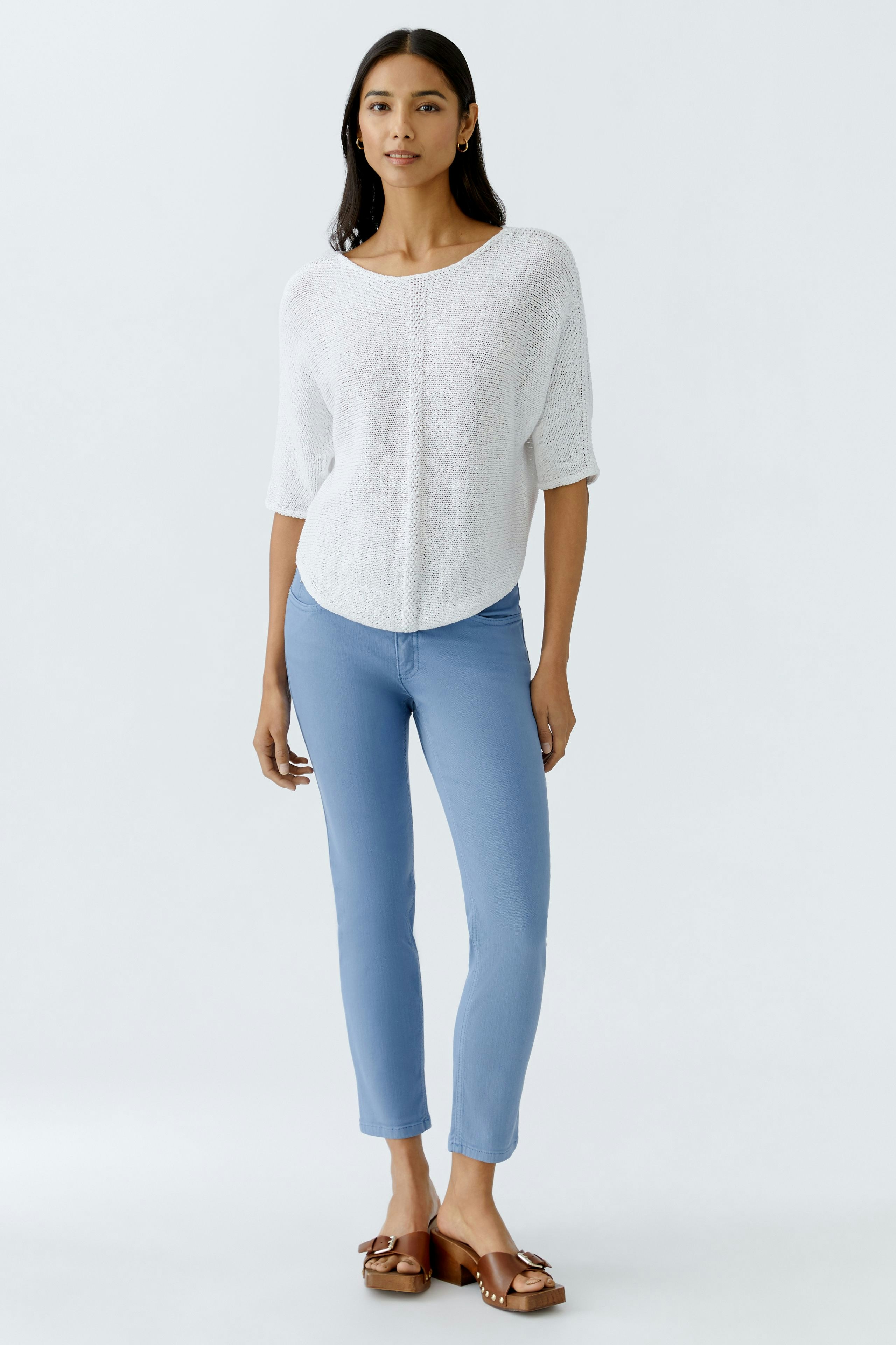 Damen-Pullover: Frau in weißem, lässigem Strickpullover mit kurzen Ärmeln und blauen Jeans.