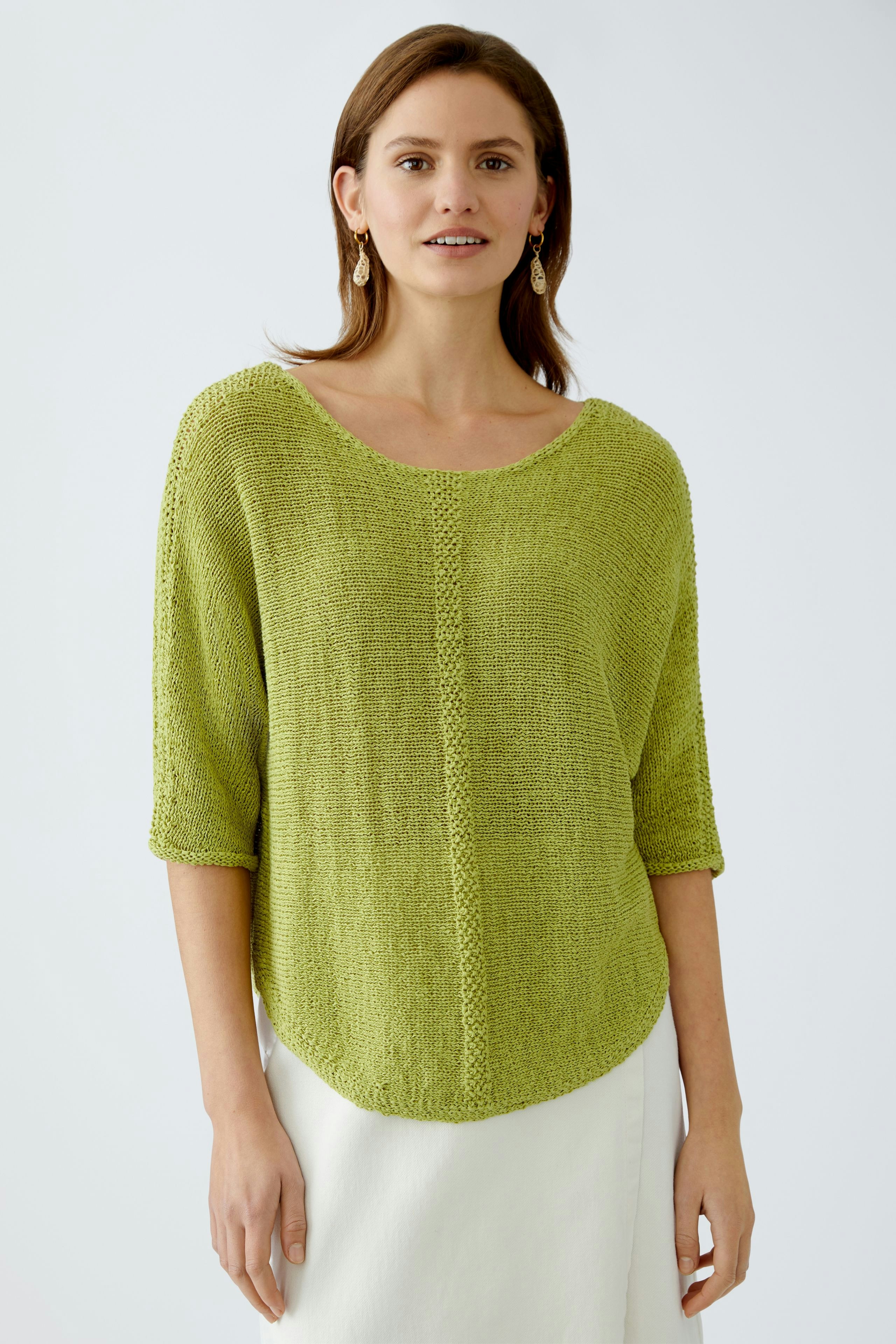 Damen-Pullover: Frau in einem leichten, grünen Strickpullover mit weitem Schnitt und 3/4-Ärmeln.