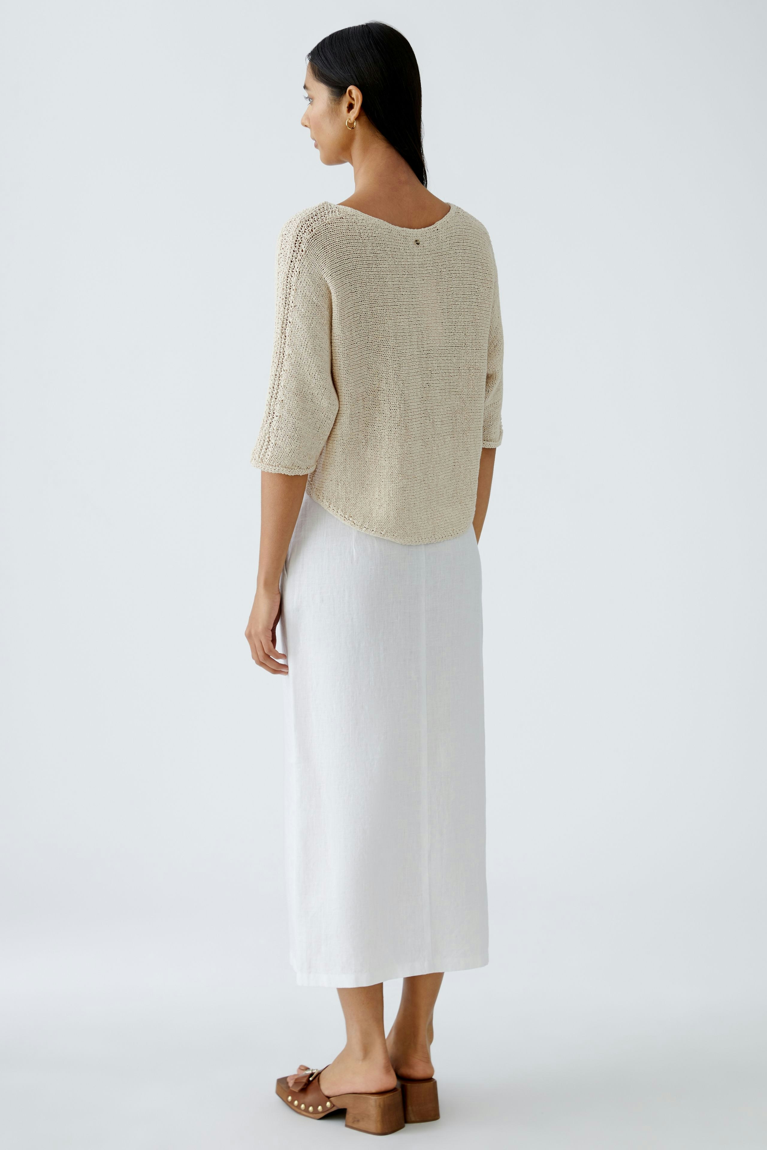 Beiger Damen-Pullover: Frau mit lässigem, leichtem Strickpullover und elegantem Rock von hinten.