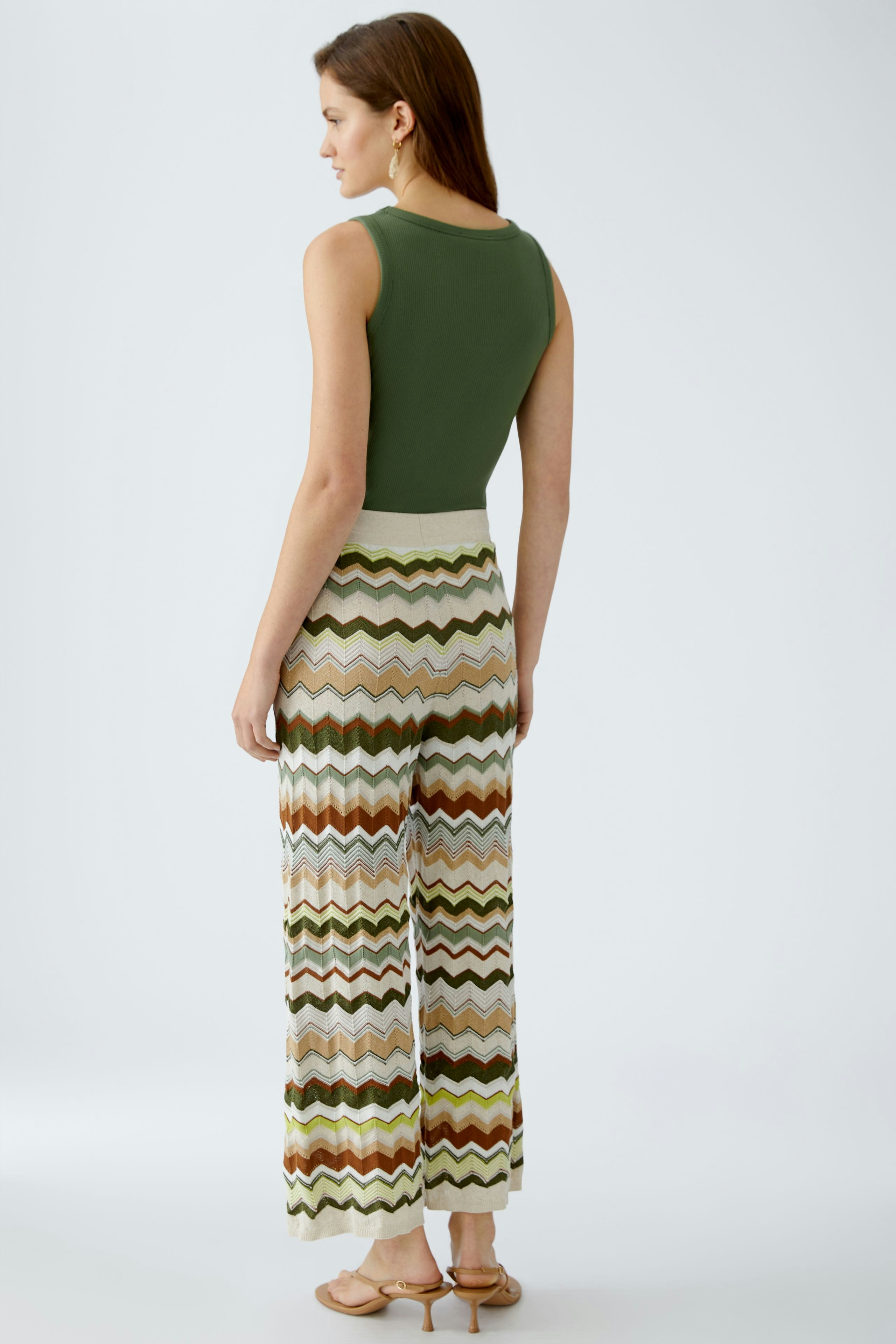 Moderne Damen-Strickhose: Frau in farbenfrohen, gestreiften Strickhosen mit lässigem Oberteil.