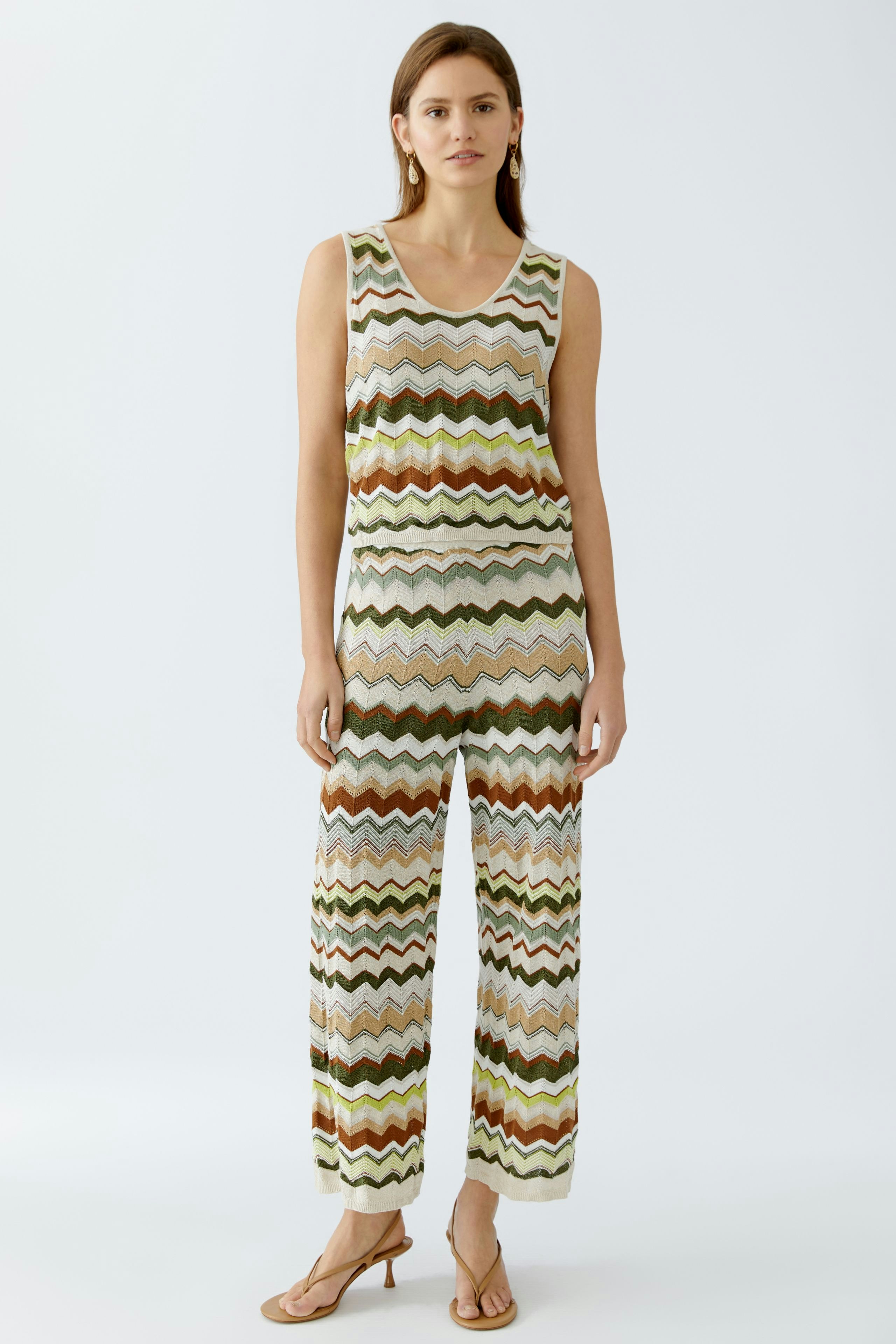 Moderne Damen-Strickhose: Frau in farbenfroher Strickhose mit Wellenmuster und passendem Oberteil.