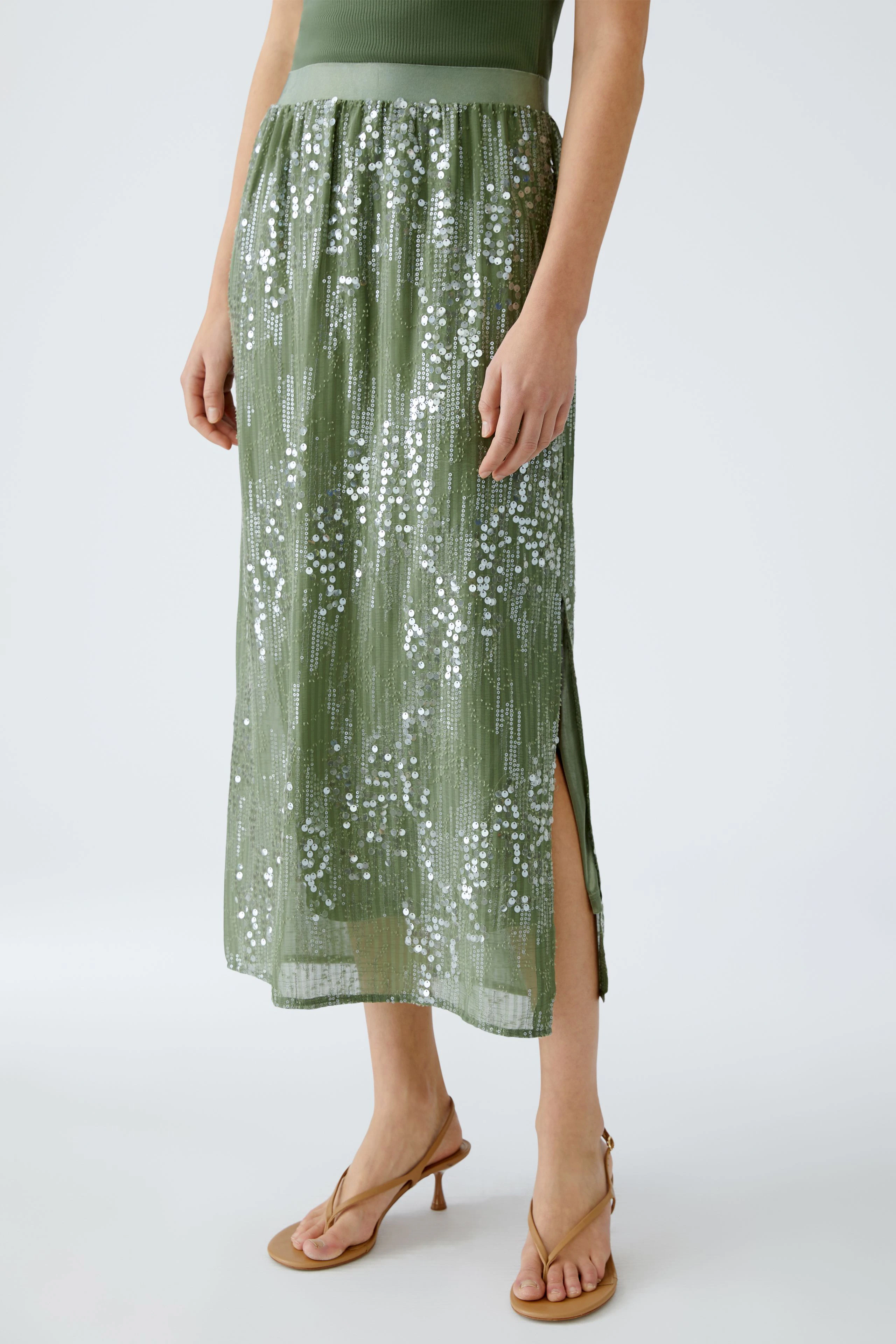 Elegant pencil skirt: Woman in a shimmering green skirt with a side slit, perfect for stylish occasions.