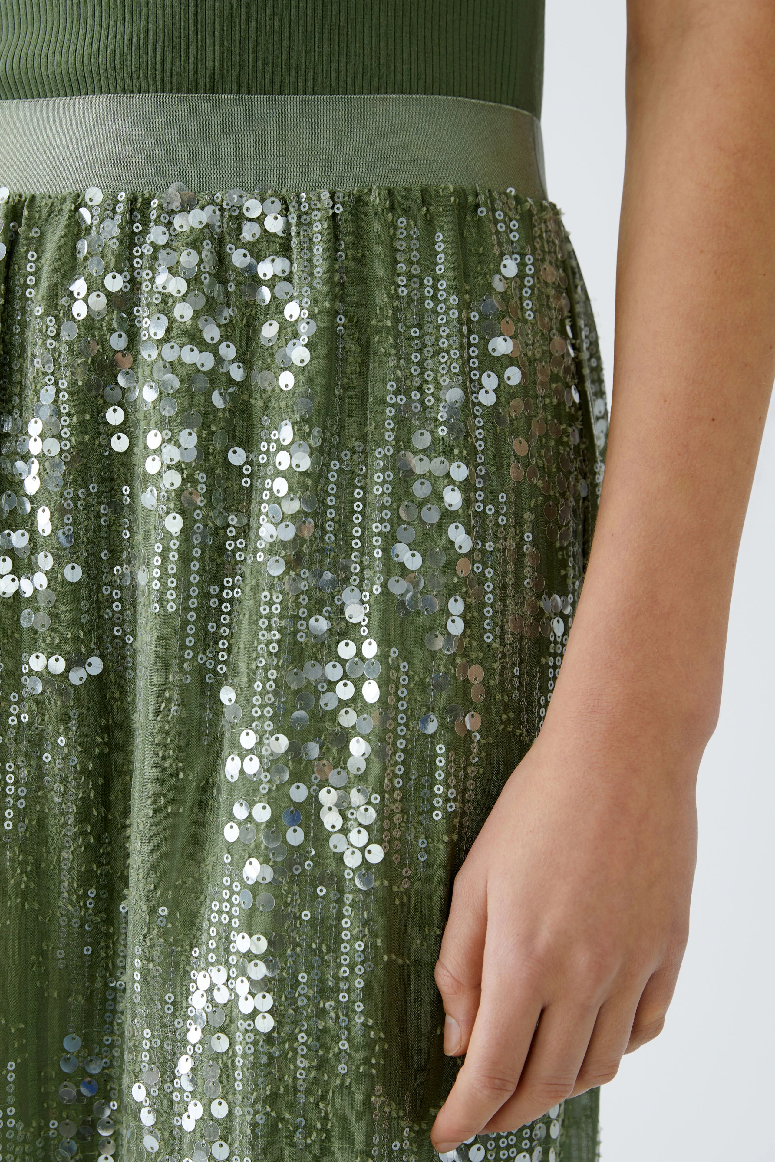 Elegant pencil skirt: A woman showcases a shimmering green pencil skirt adorned with sequins.