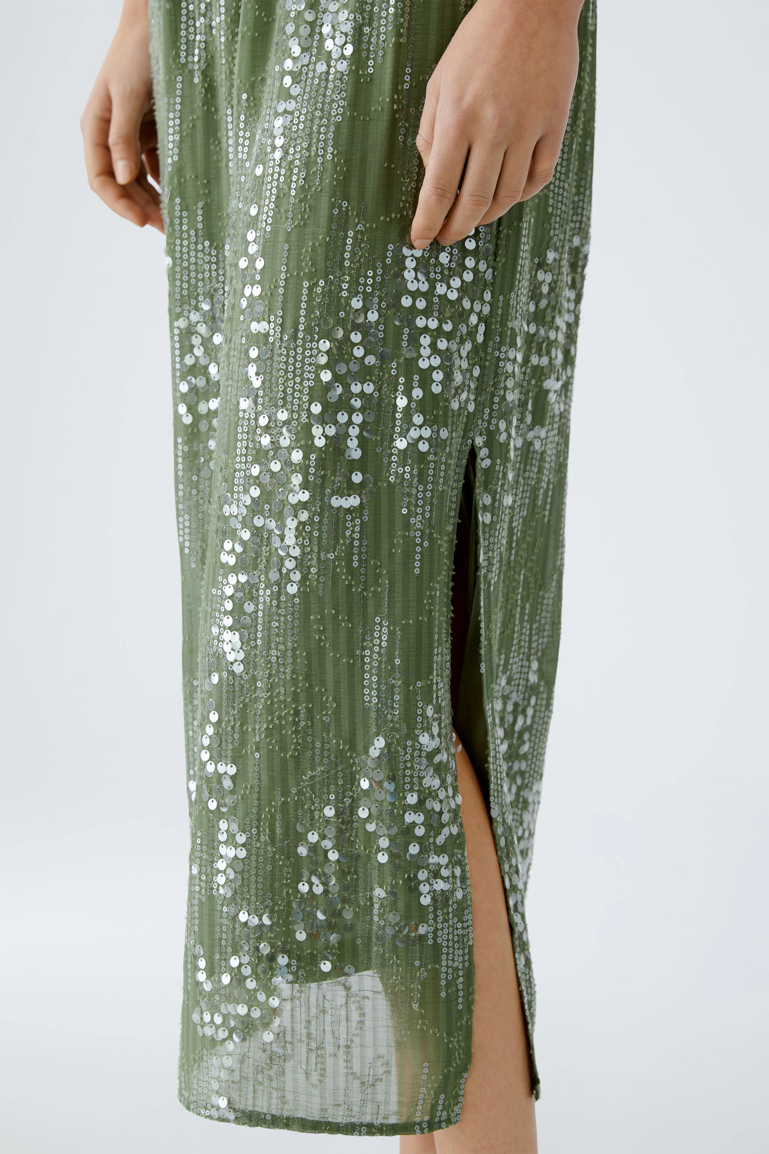 Elegant pencil skirt: A woman showcases a shimmering green pencil skirt with side slits.