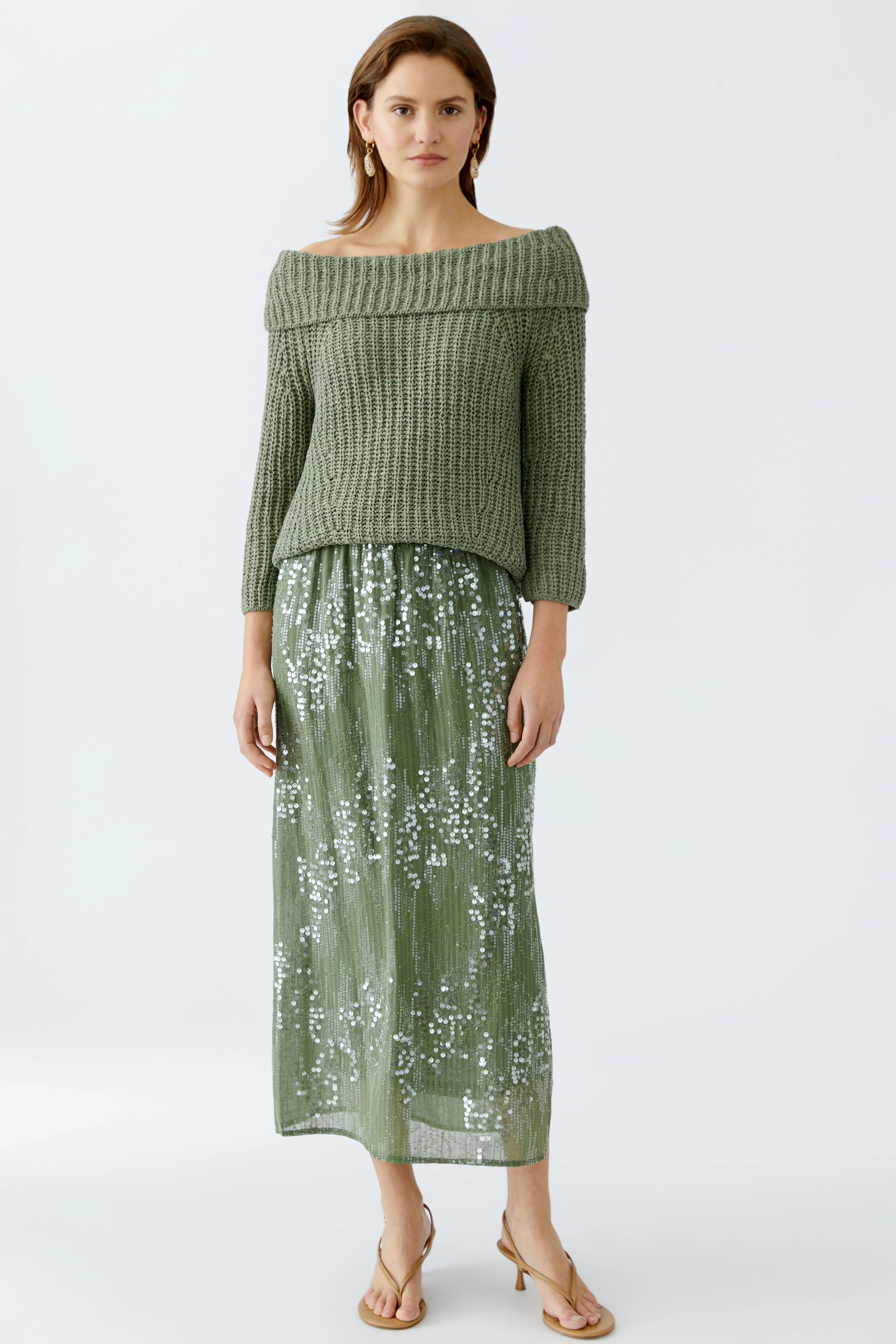 Elegant pencil skirt: A woman in a stylish off-shoulder pullover and shimmering green pencil skirt.