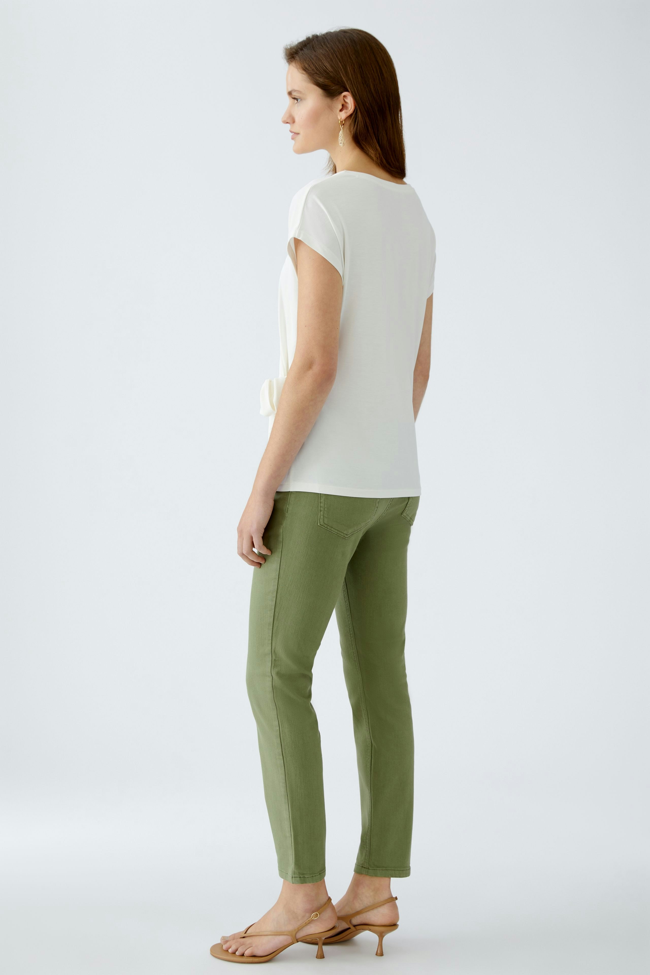 Elegantes Damen-T-Shirt: Frau in weißem T-Shirt mit lässigem Schnitt und grünem Hosen.