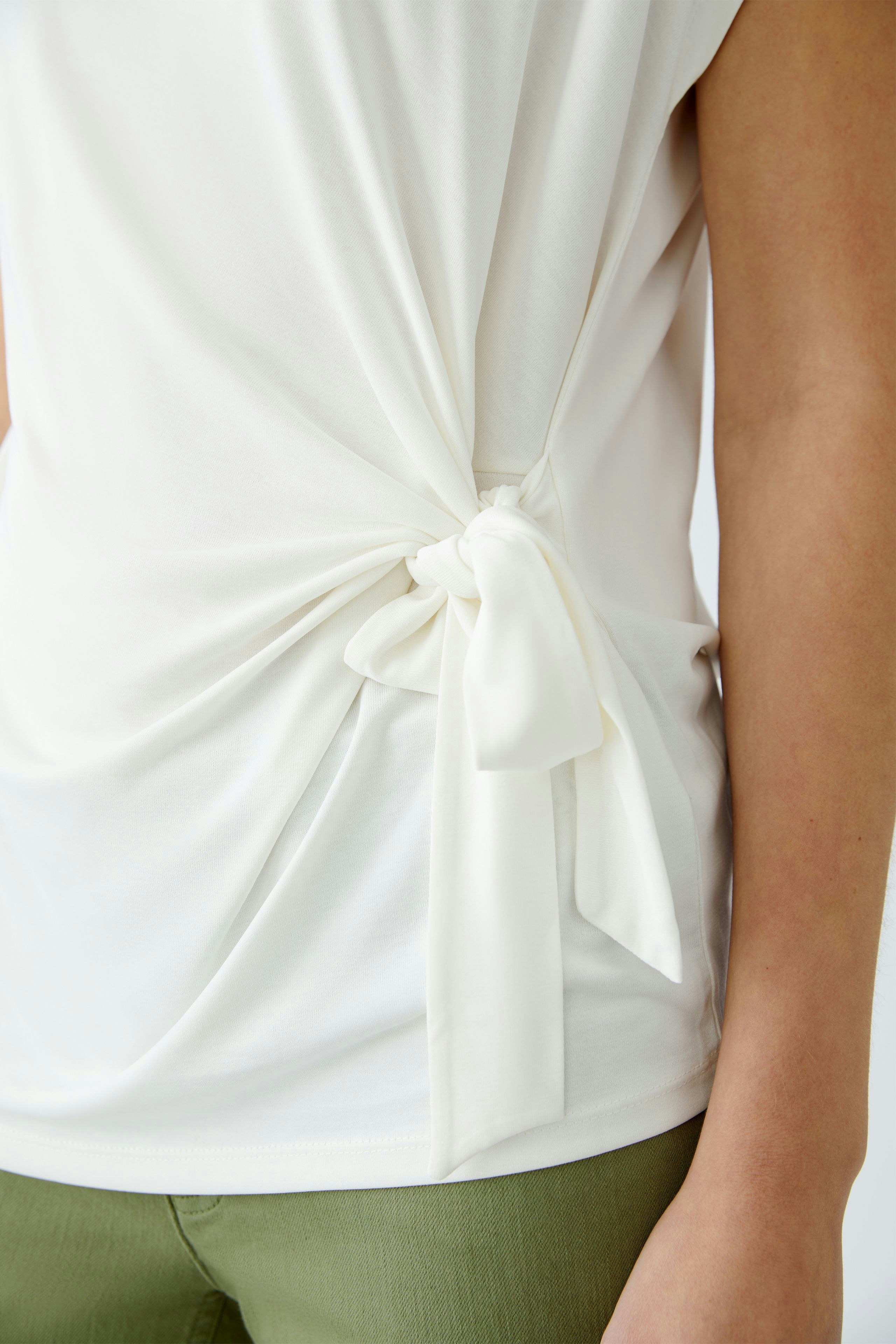 Elegantes Damen-T-Shirt: Frau in weißem T-Shirt mit seitlichem Knoten, lässig und modern.