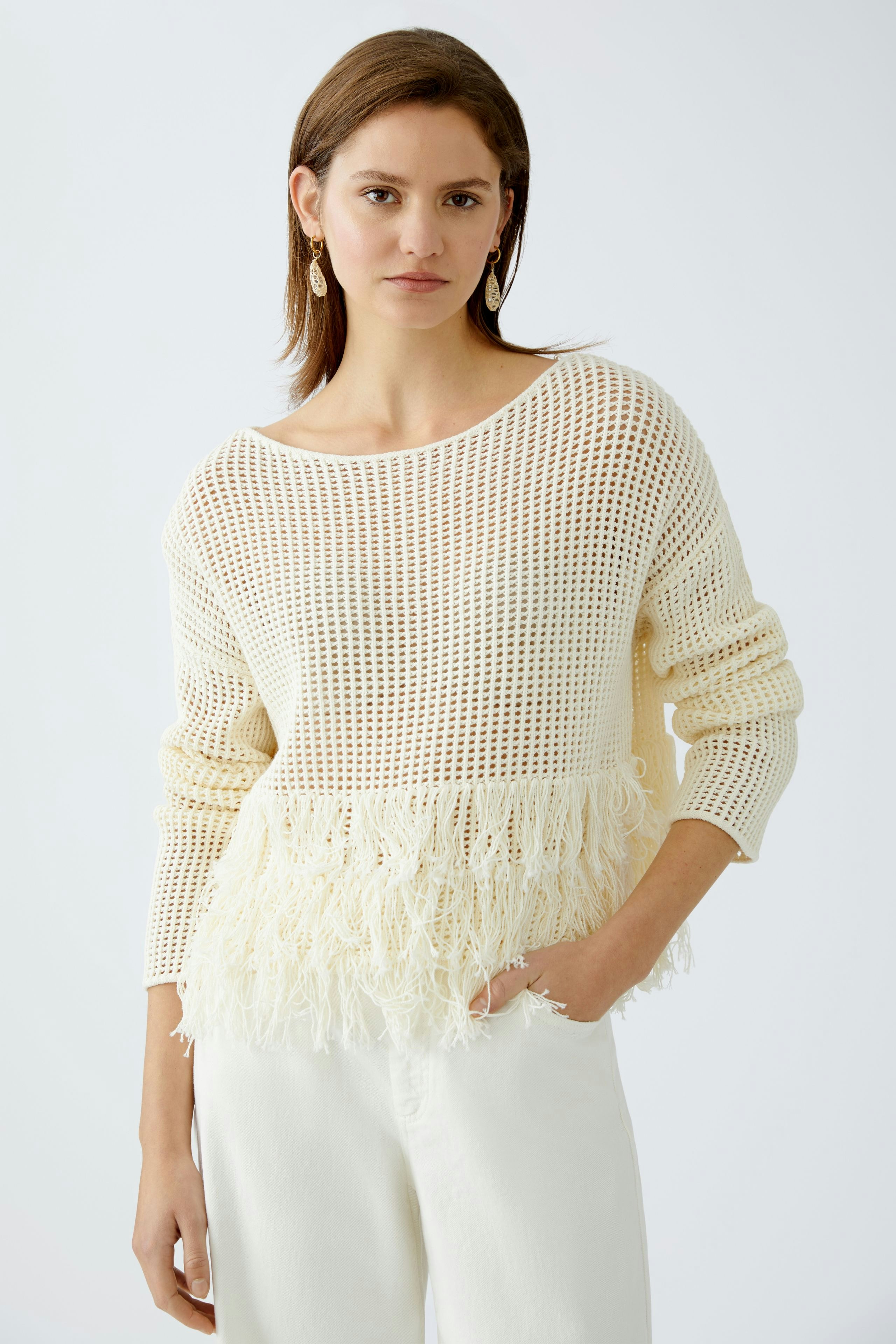 Damen-Pullover: Junge Frau in einem weißen, luftigen Strickpullover mit Fransen am Saum.