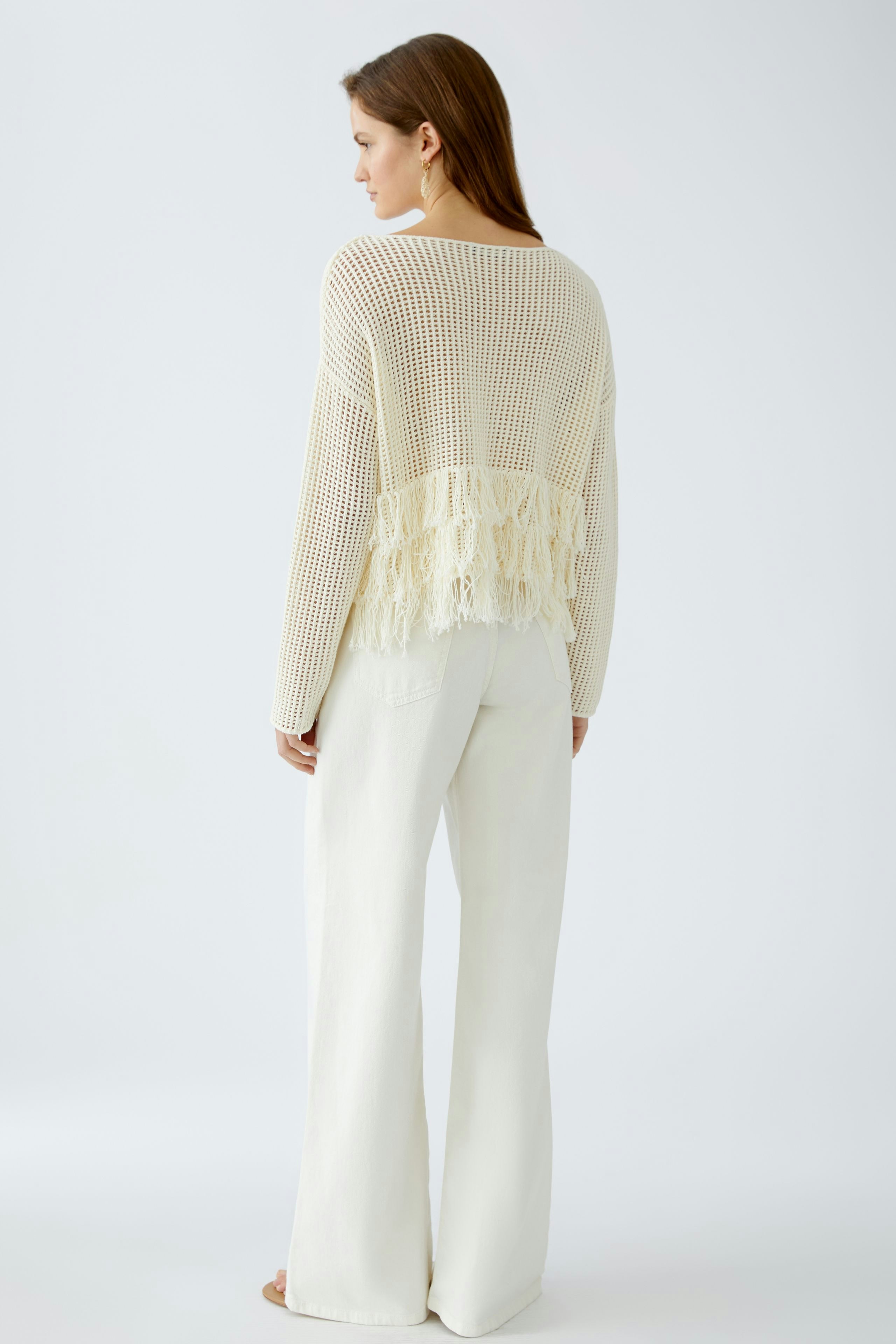 Damen-Pullover: Frau in einem hellen, luftigen Strickpullover mit Fransen, lässig und modern.