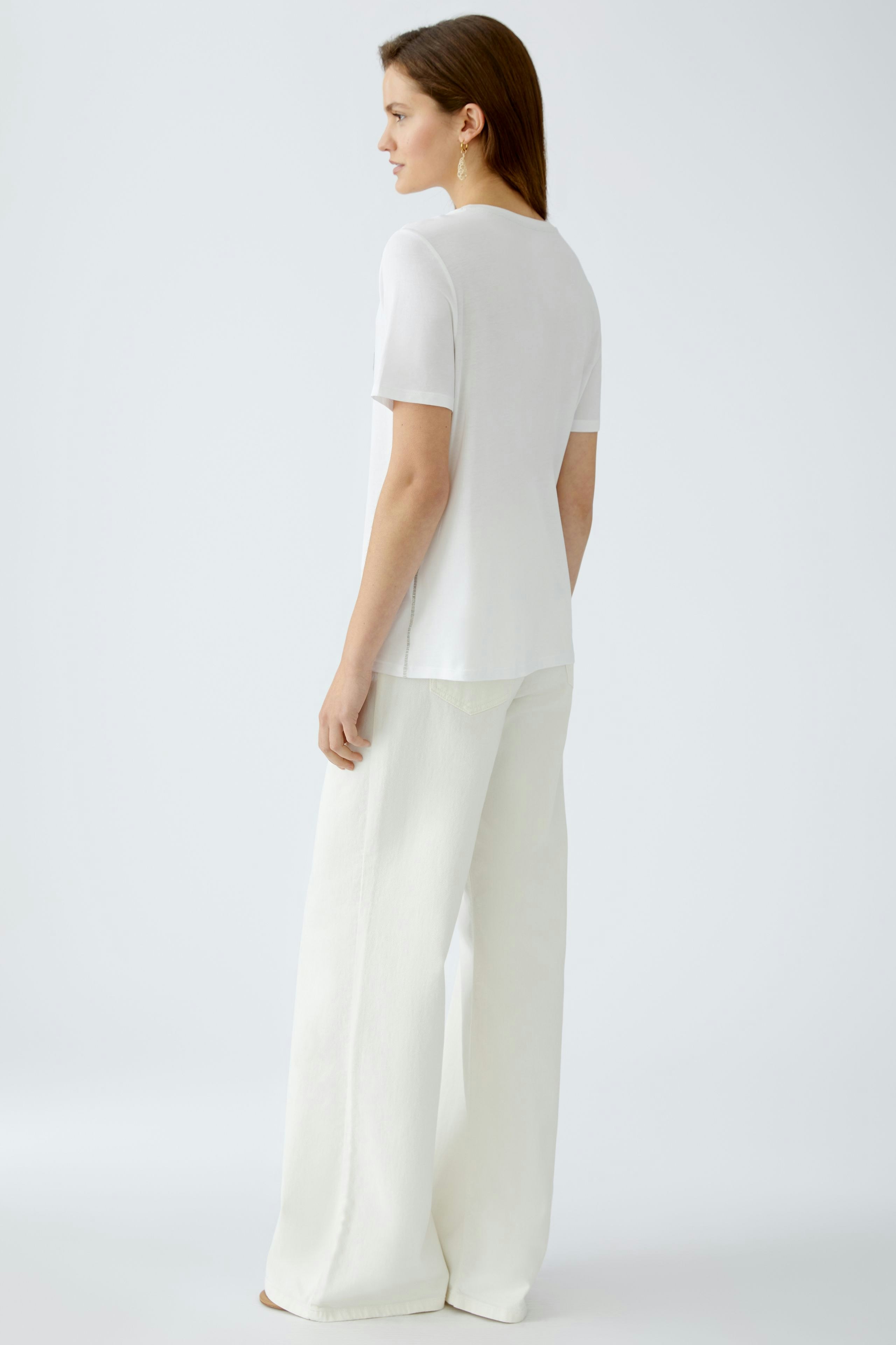 Elegant women's T-shirt: A woman in a white T-shirt paired with light trousers, showcasing a simple style.
