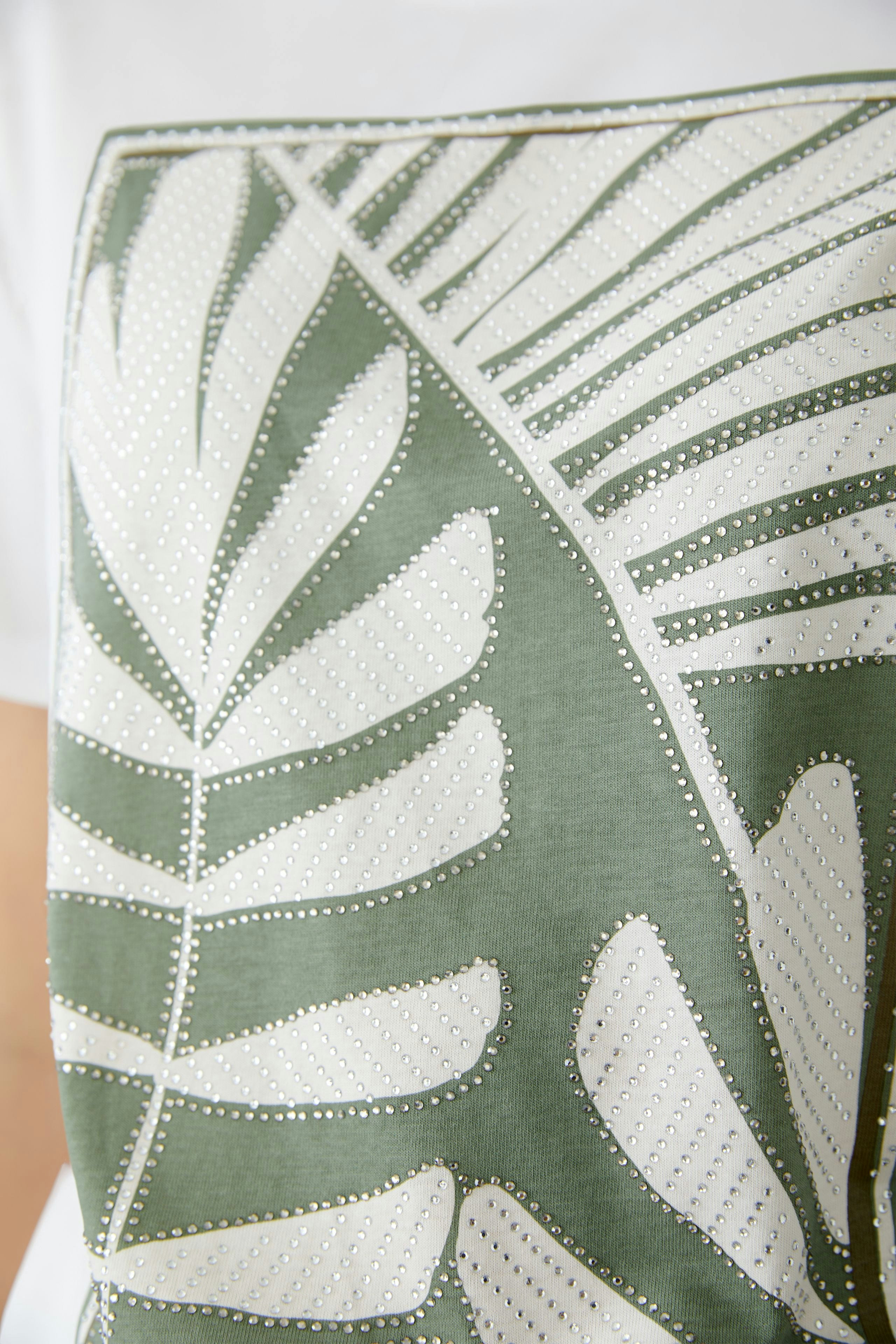 Stylish women's T-shirt featuring a green leaf print, perfect for casual summer outfits.