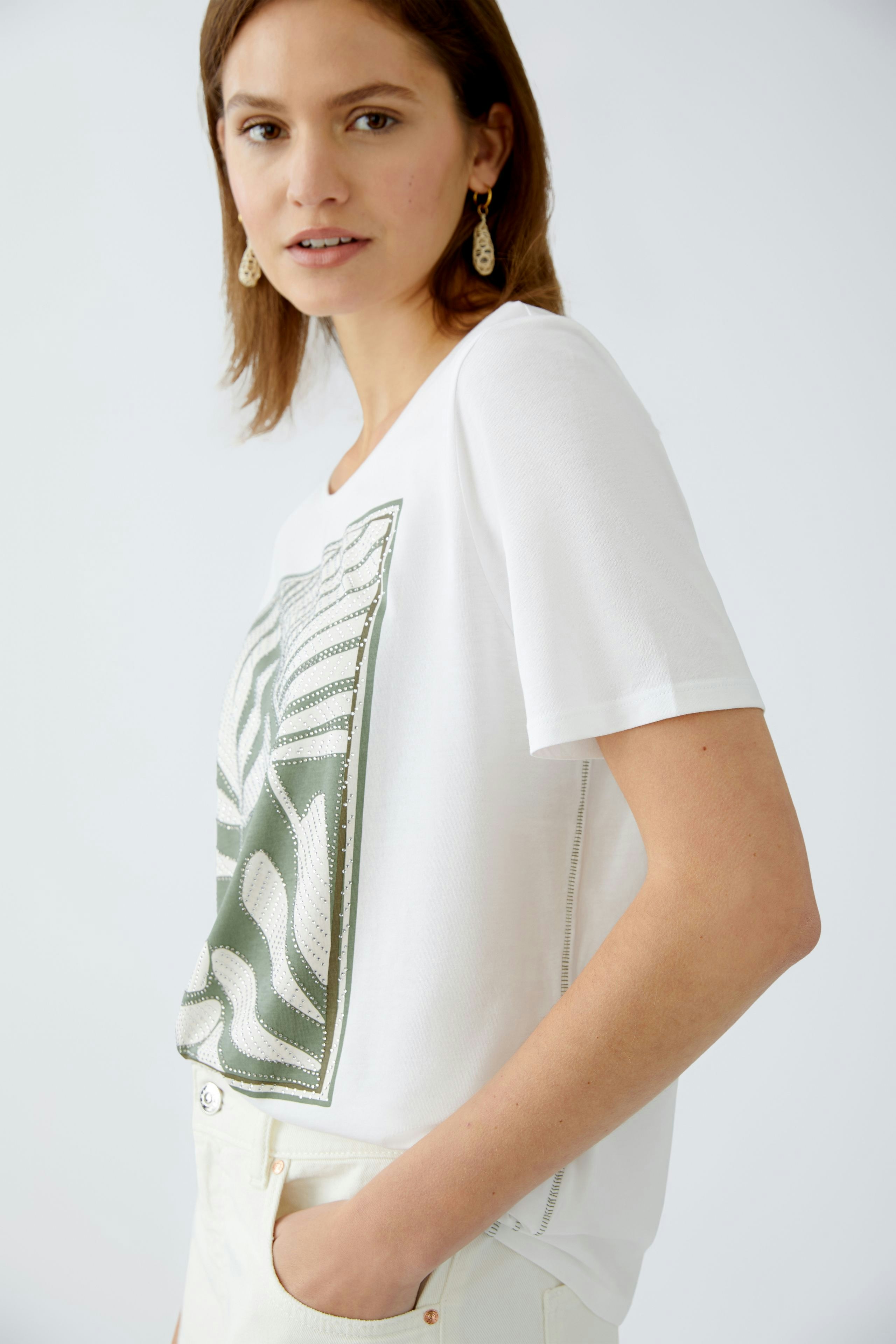 Stylish women's T-shirt: A woman in a white tee with a green graphic design, exuding casual elegance.