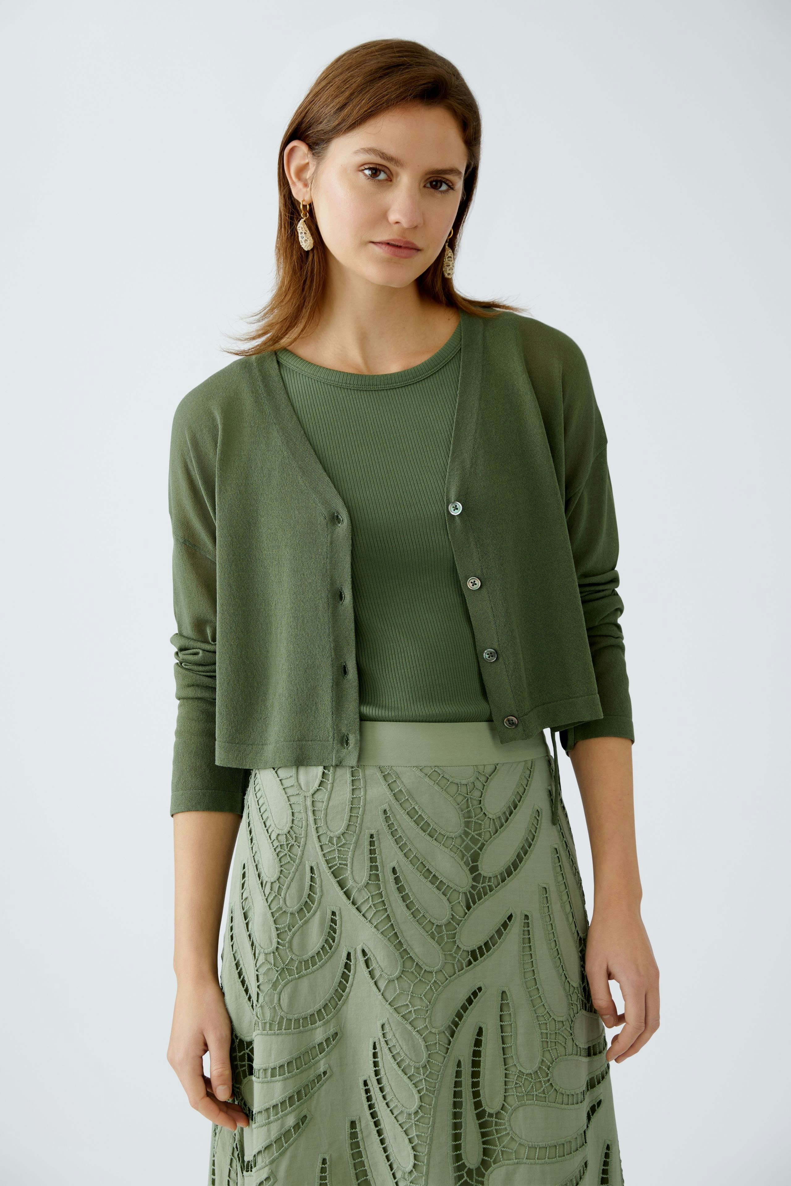 Stylish women's cardigan: A woman in a green cardigan over a matching top, exuding elegance.