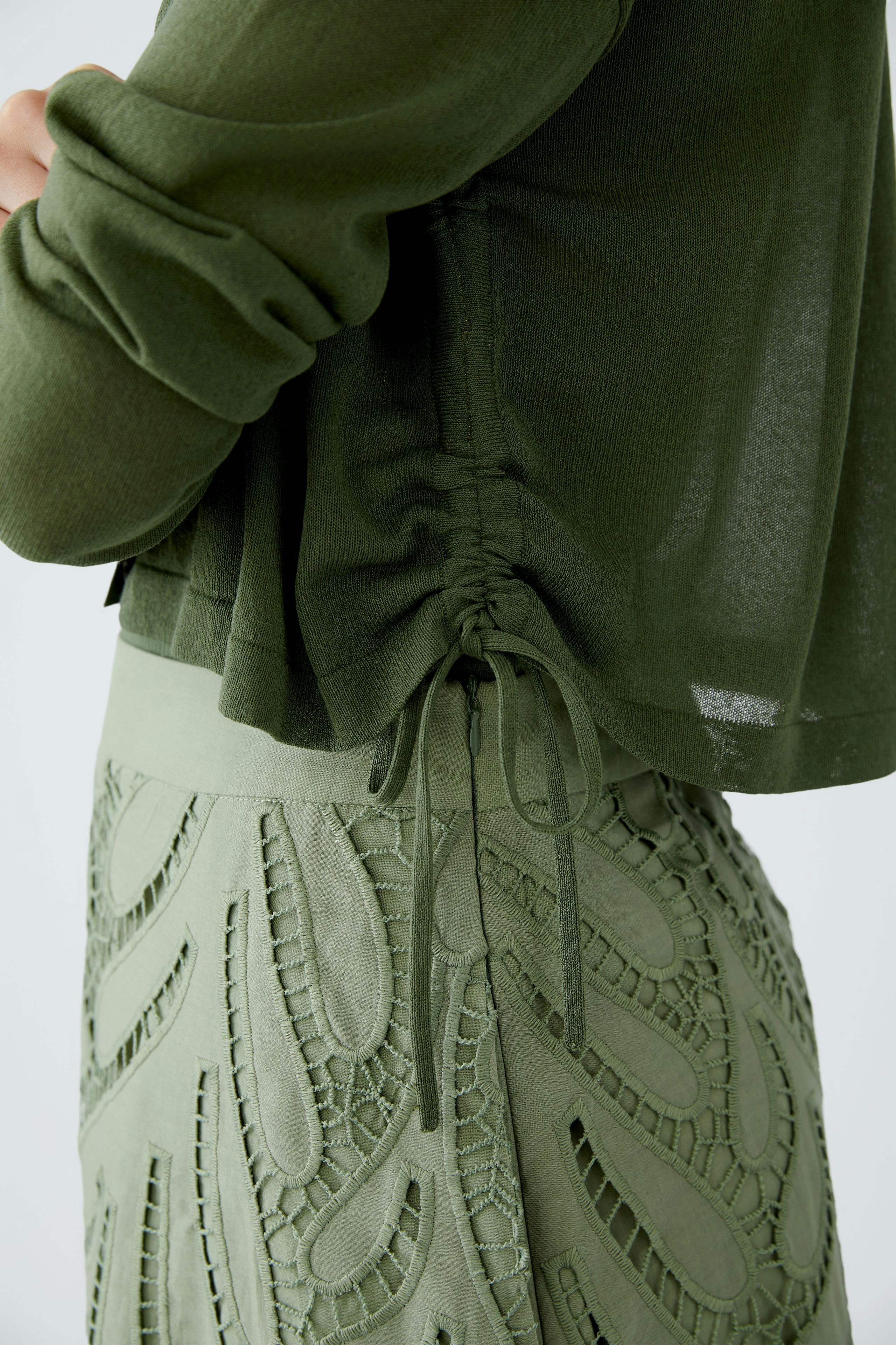 Stylish women's cardigan in soft green, featuring a gathered back detail for a modern touch.