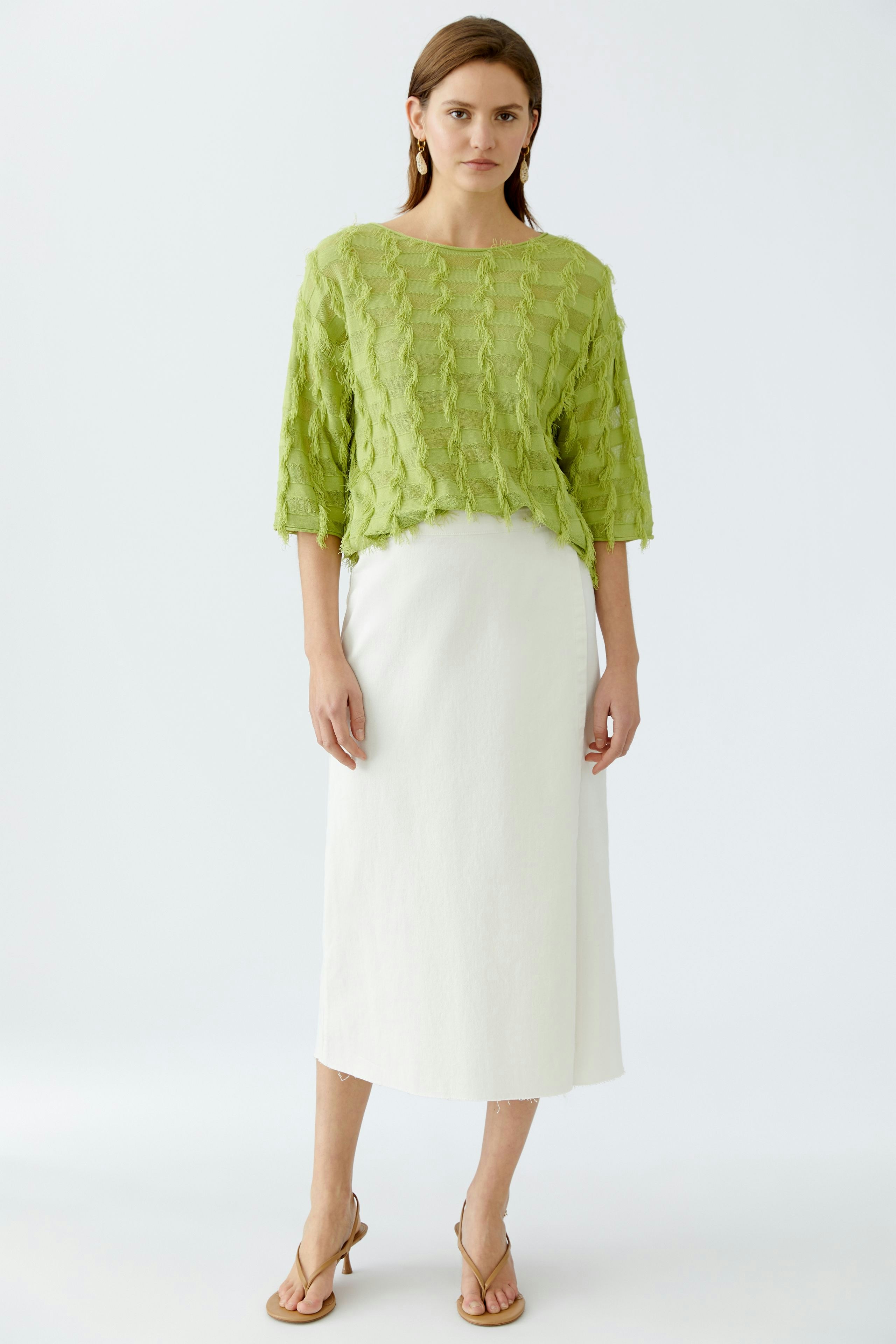 Stylish women's pullover: A woman in a textured green pullover paired with a white skirt.